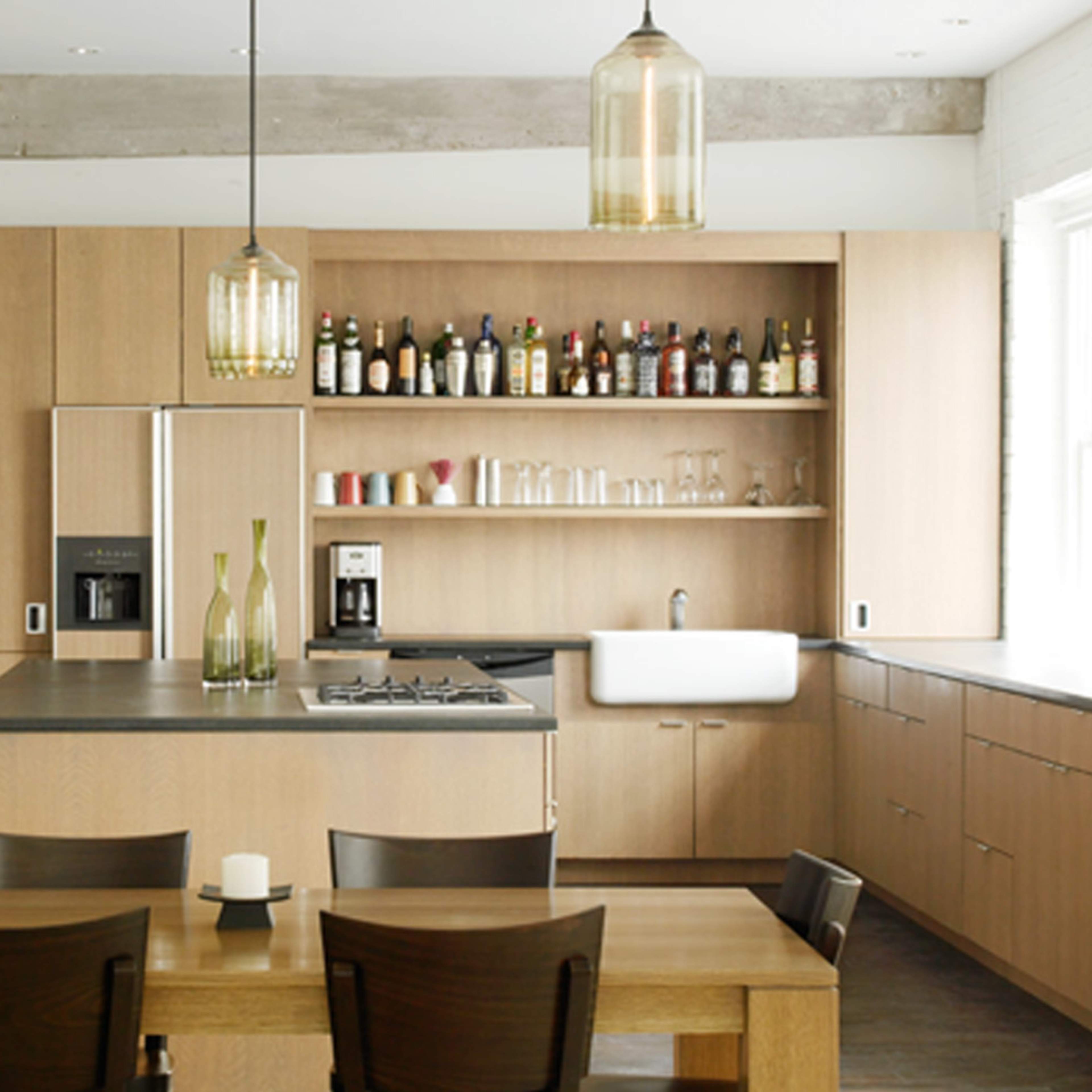 A modern kitchen features wooden cabinetry, a central island with a stovetop, and a dining table set with candles.