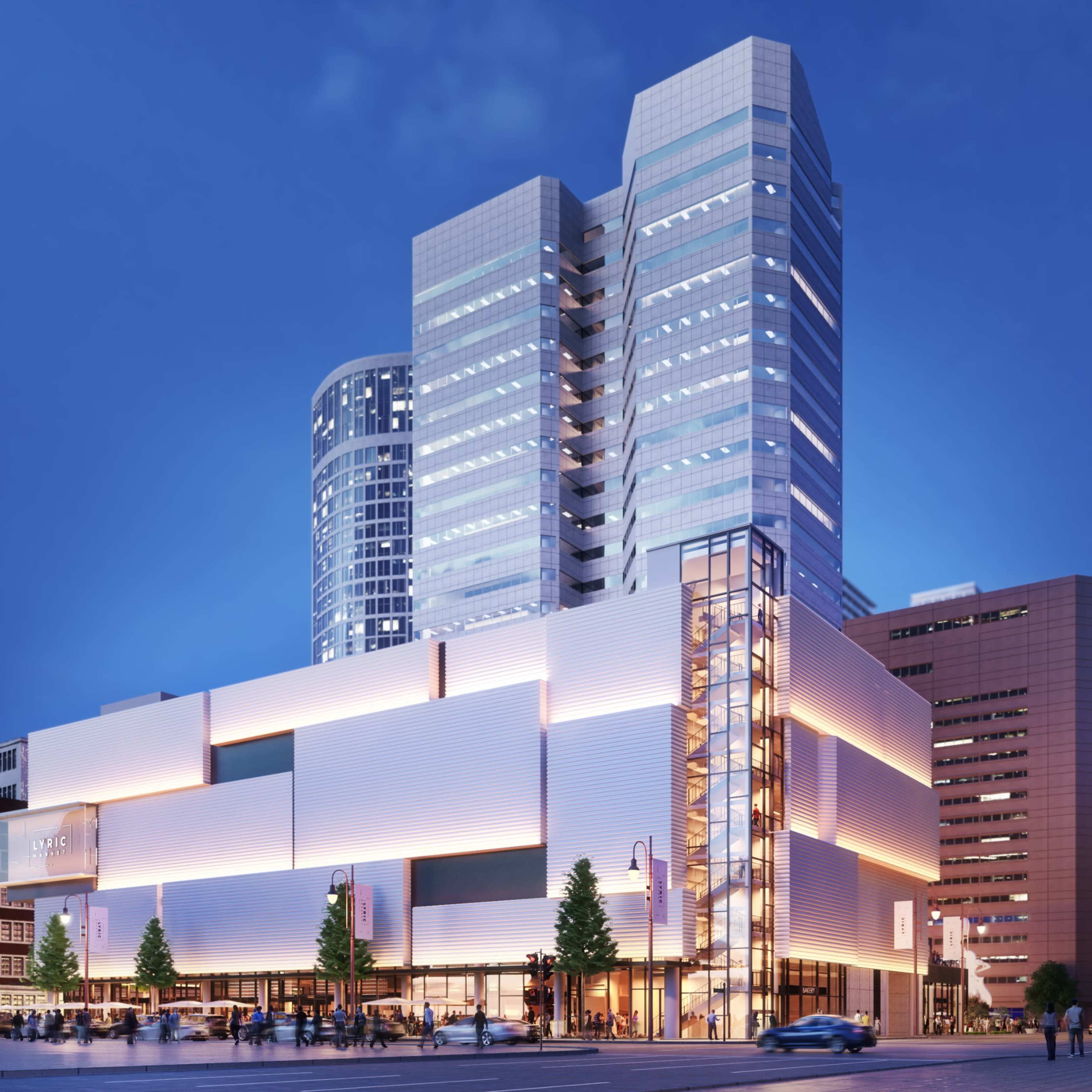 A modern multi-story building with sleek architecture illuminated at dusk, surrounded by urban skyscrapers and city streets.