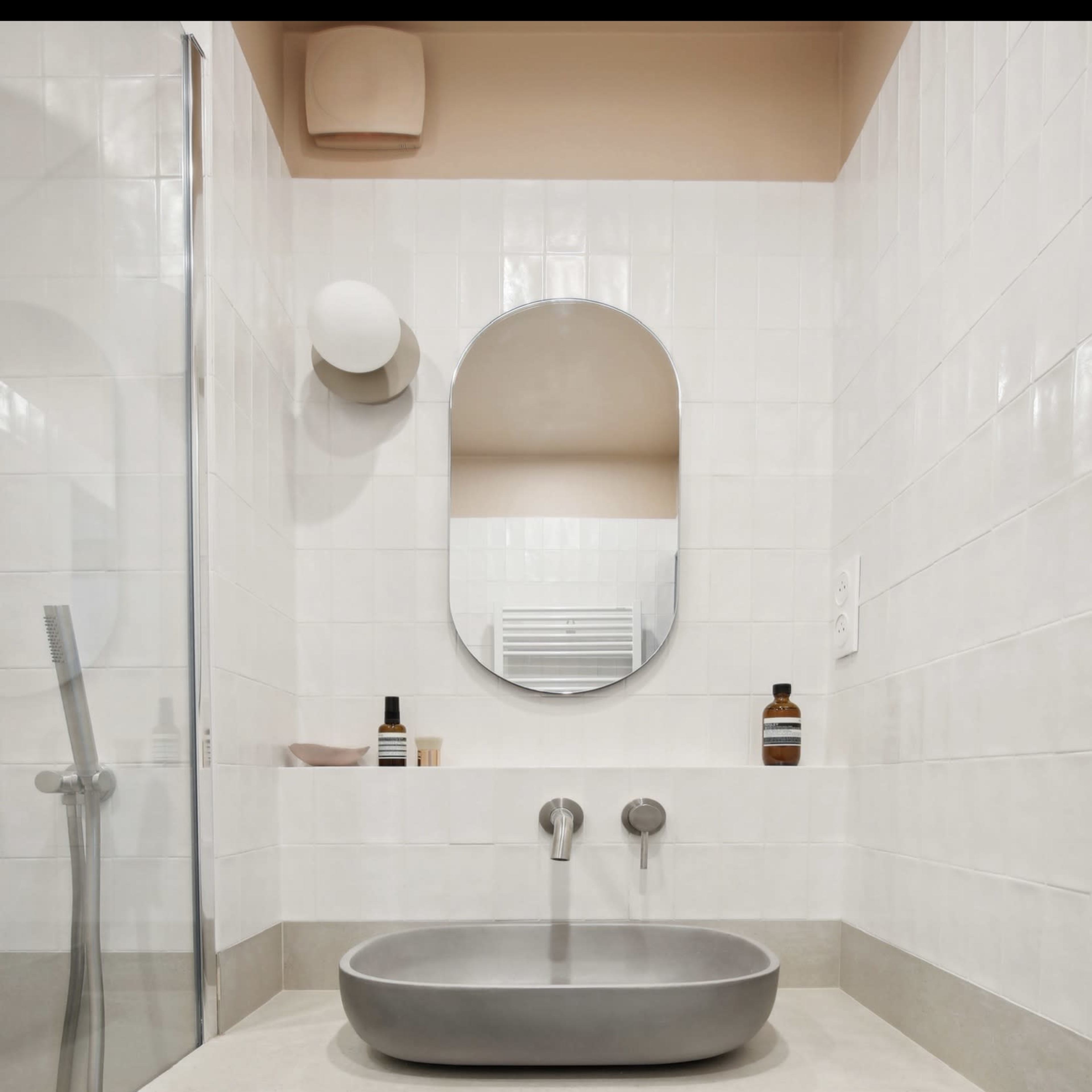 A modern bathroom features a sleek basin on a counter, a mirror above, and a glass shower enclosure.