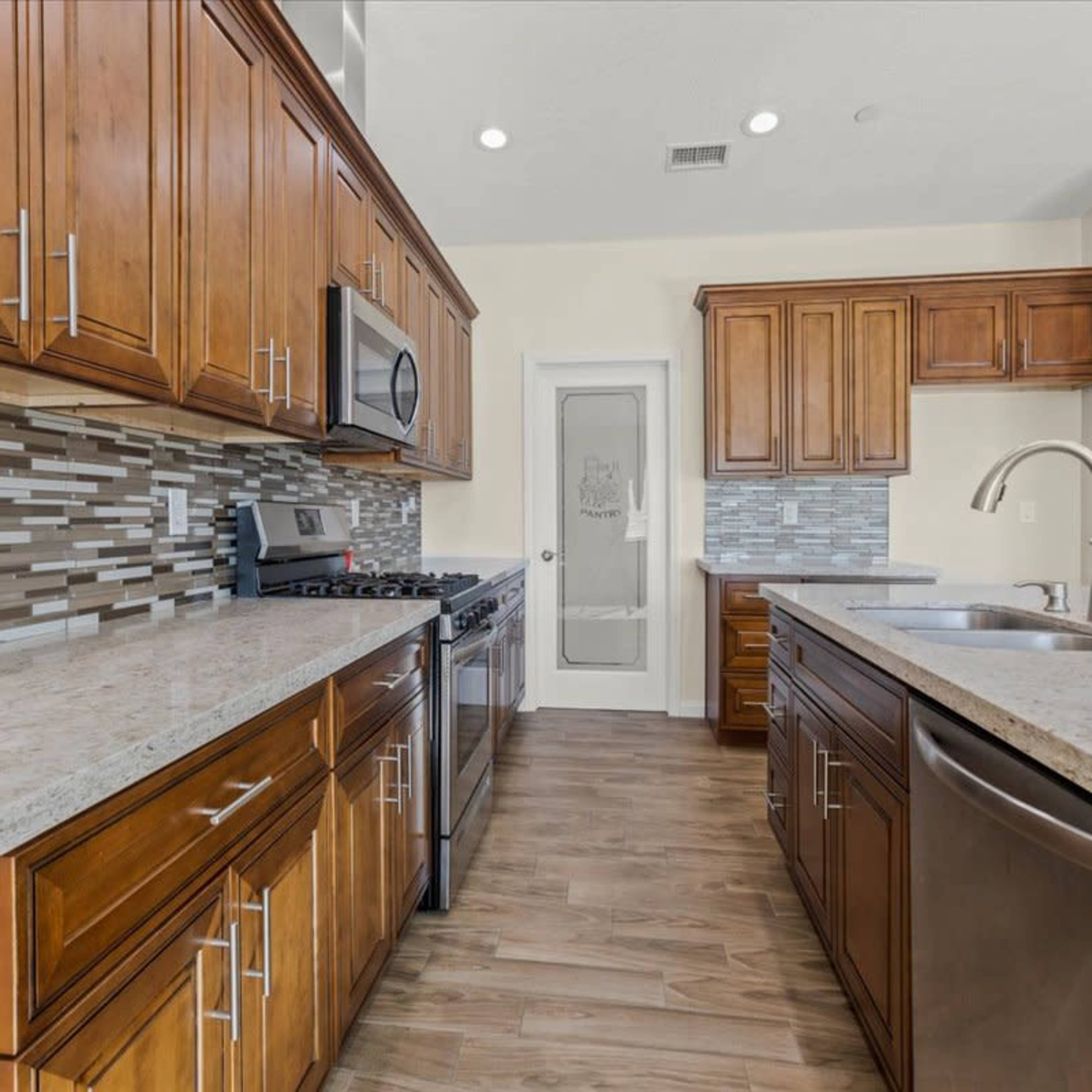 A modern kitchen with wooden cabinets, a granite countertop, and a stainless steel appliance setup.