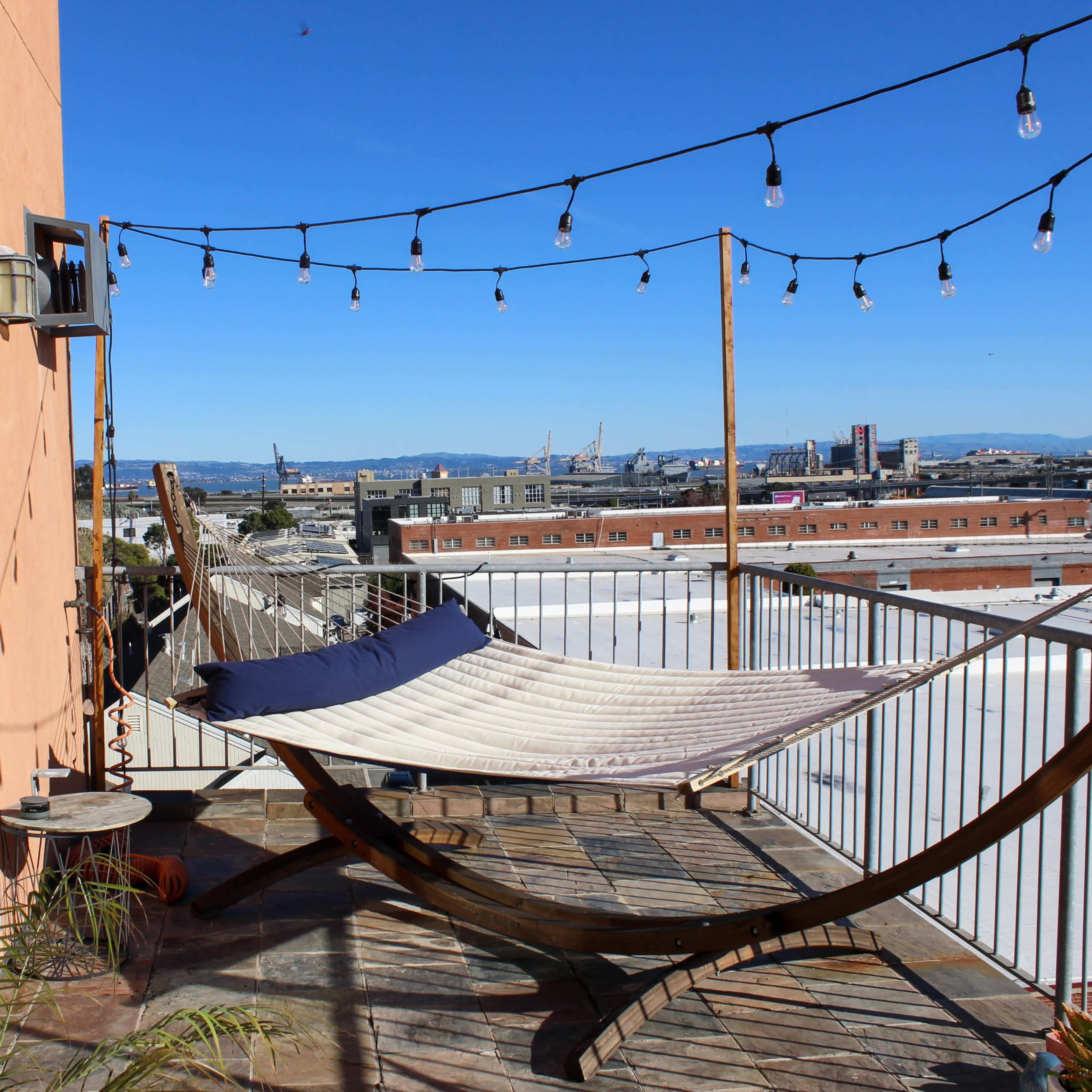 A rooftop terrace features a hammock, string lights, and a view of the skyline.