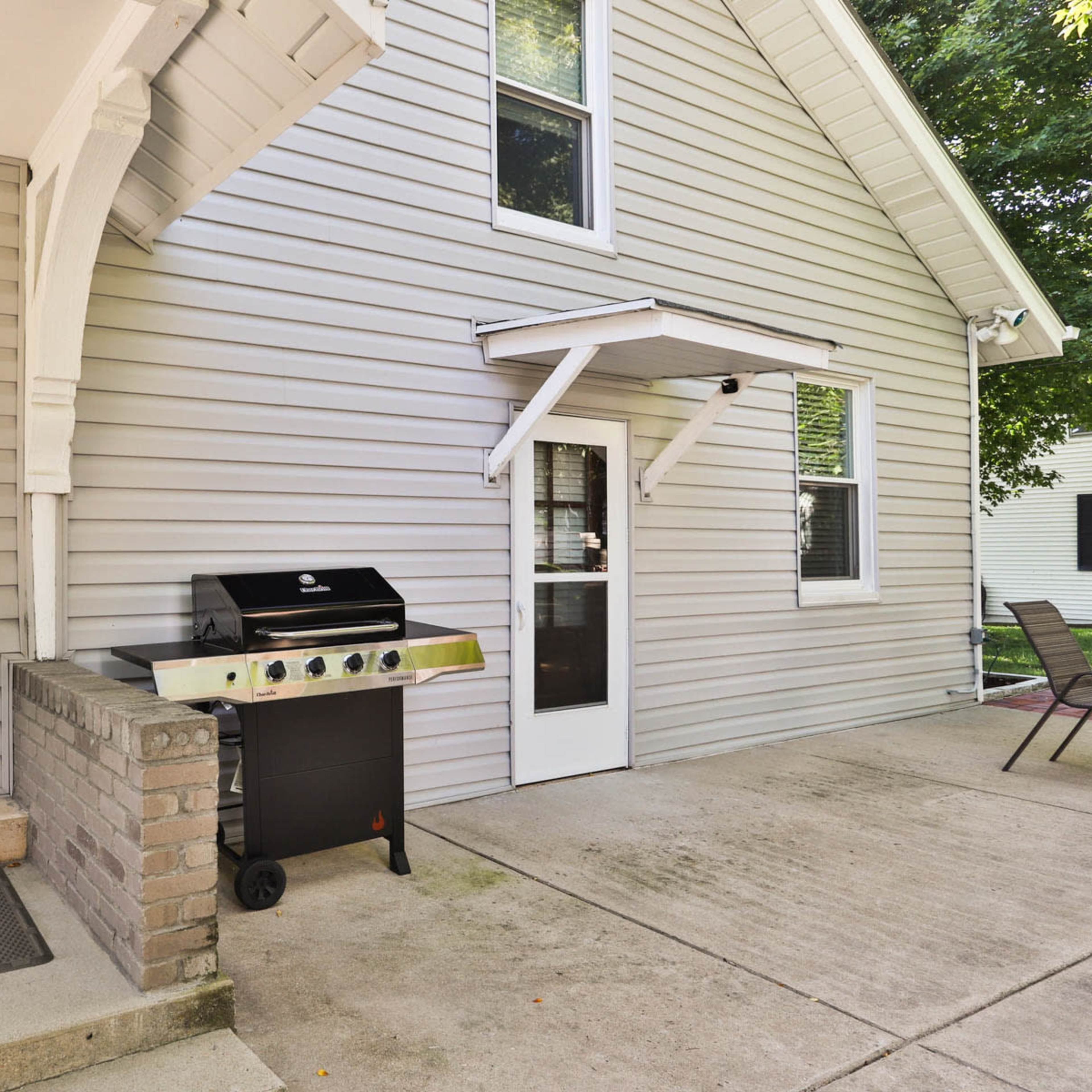 A gray house exterior with a barbecue grill positioned next to a side door and multiple windows.