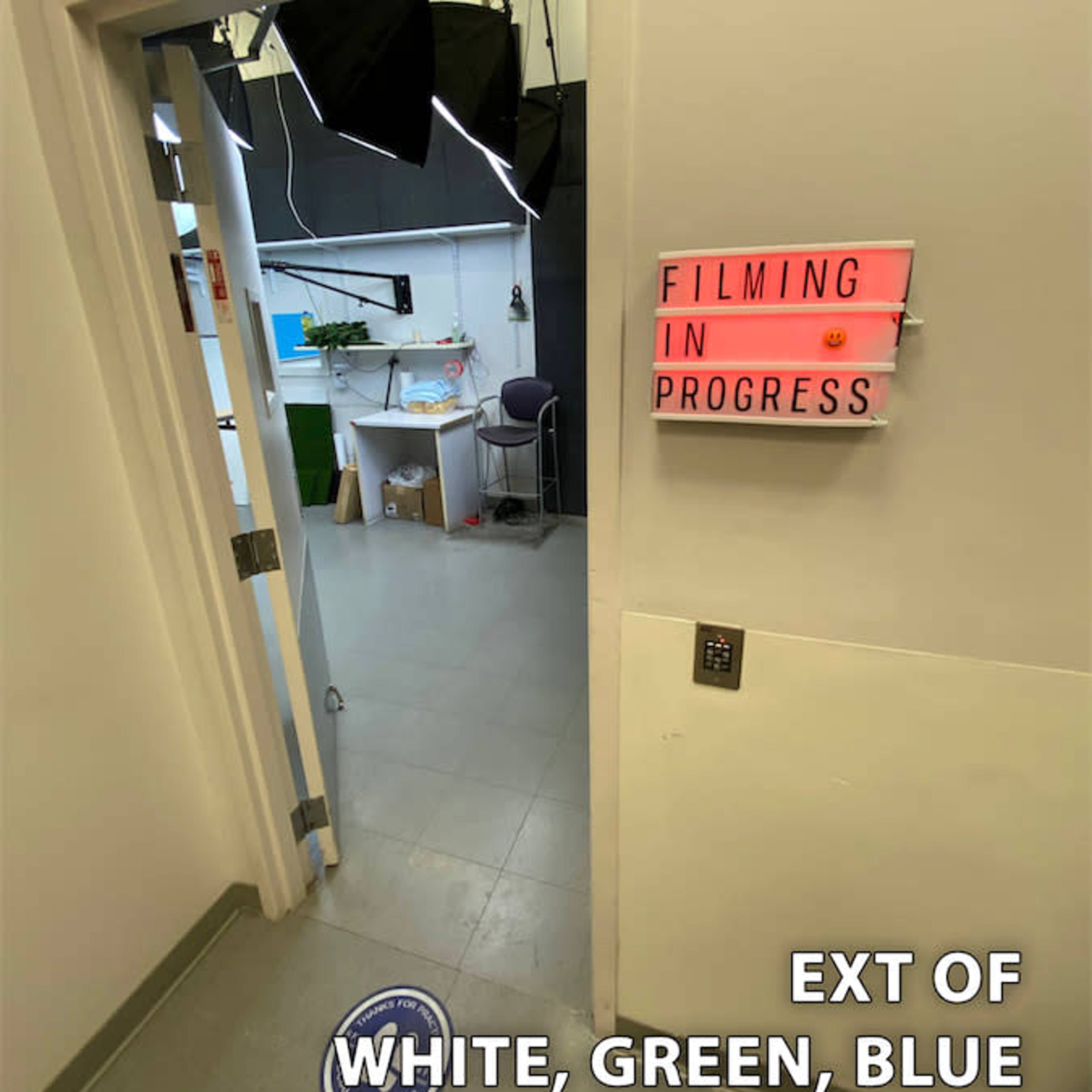 An open door leading to a room labeled "FILMING IN PROGRESS," with studio equipment visible inside, including lights and a workspace.