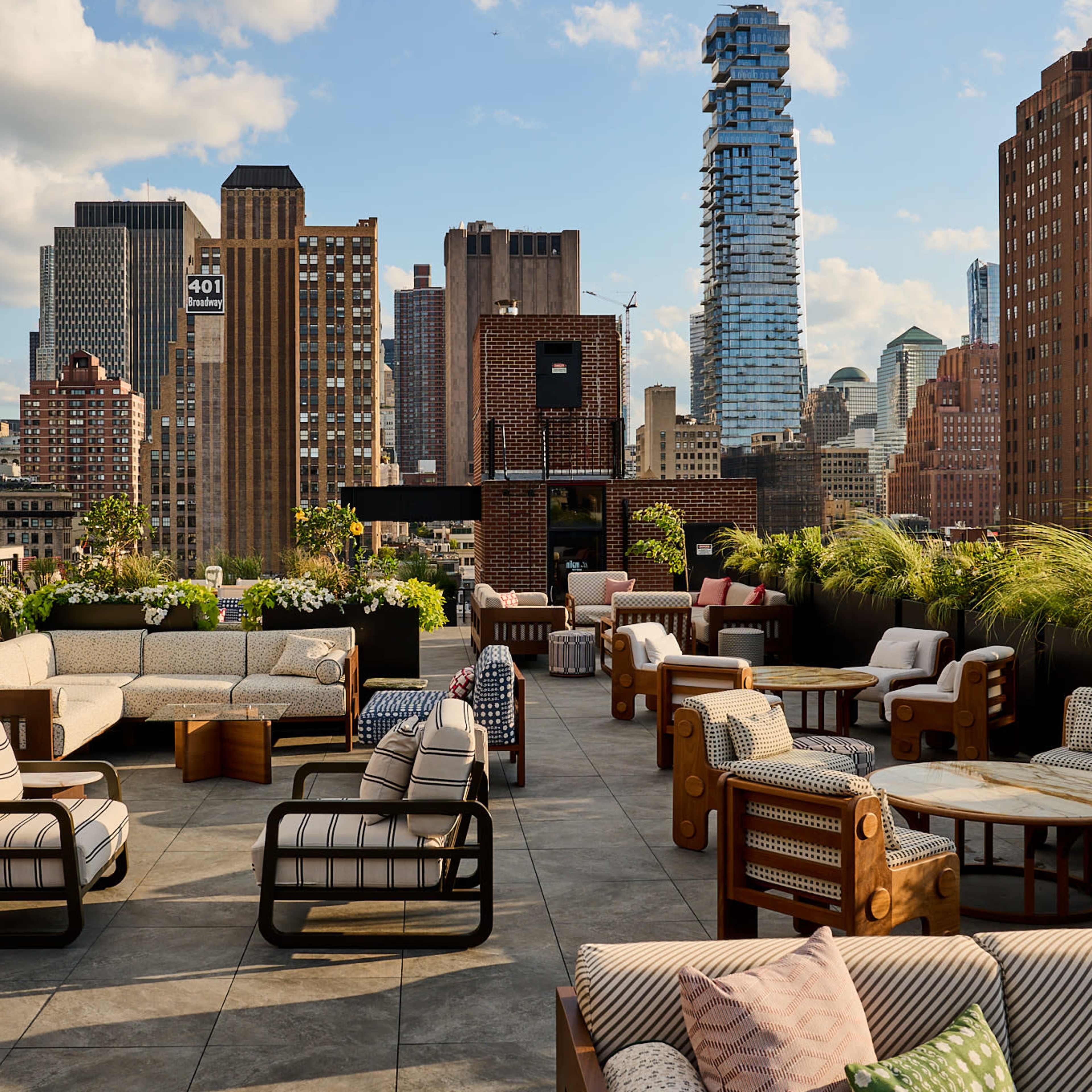 A rooftop lounge features modern seating arrangements surrounded by city skyscrapers and greenery.