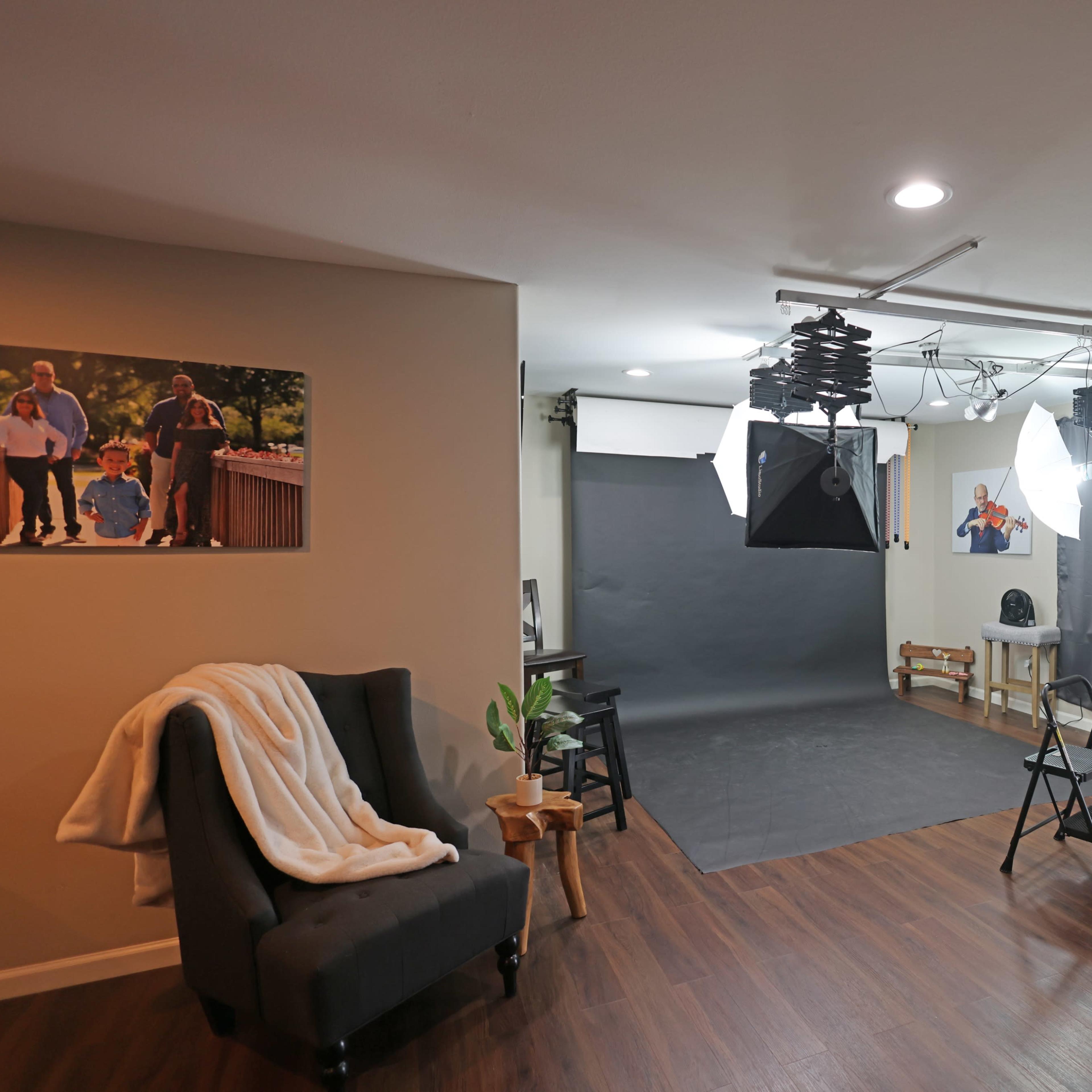 A photography studio equipped with lighting, a backdrop, and a seating area with a chair and a small table.