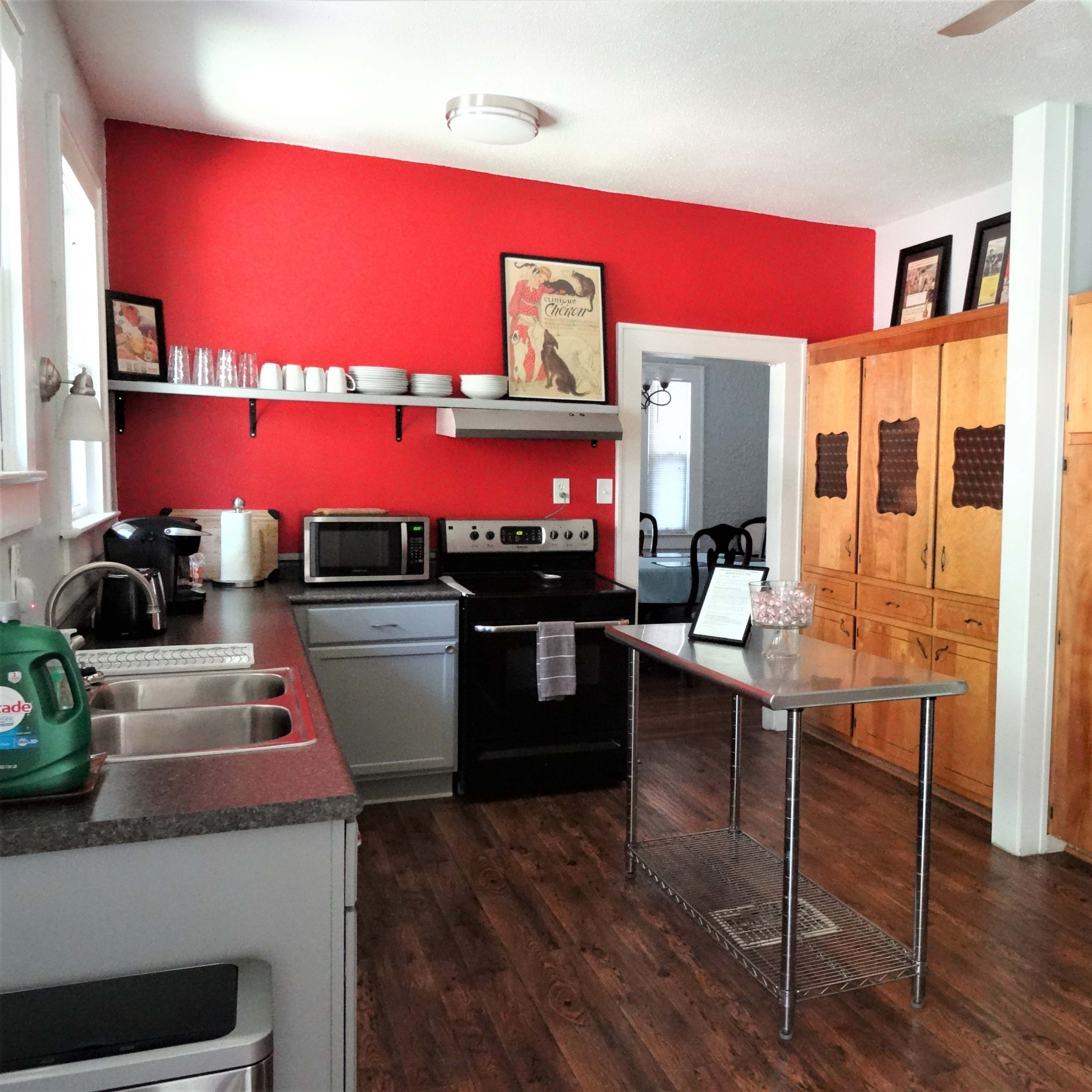 A kitchen with a red accent wall, stainless steel appliances, a central island, and wooden cabinets.