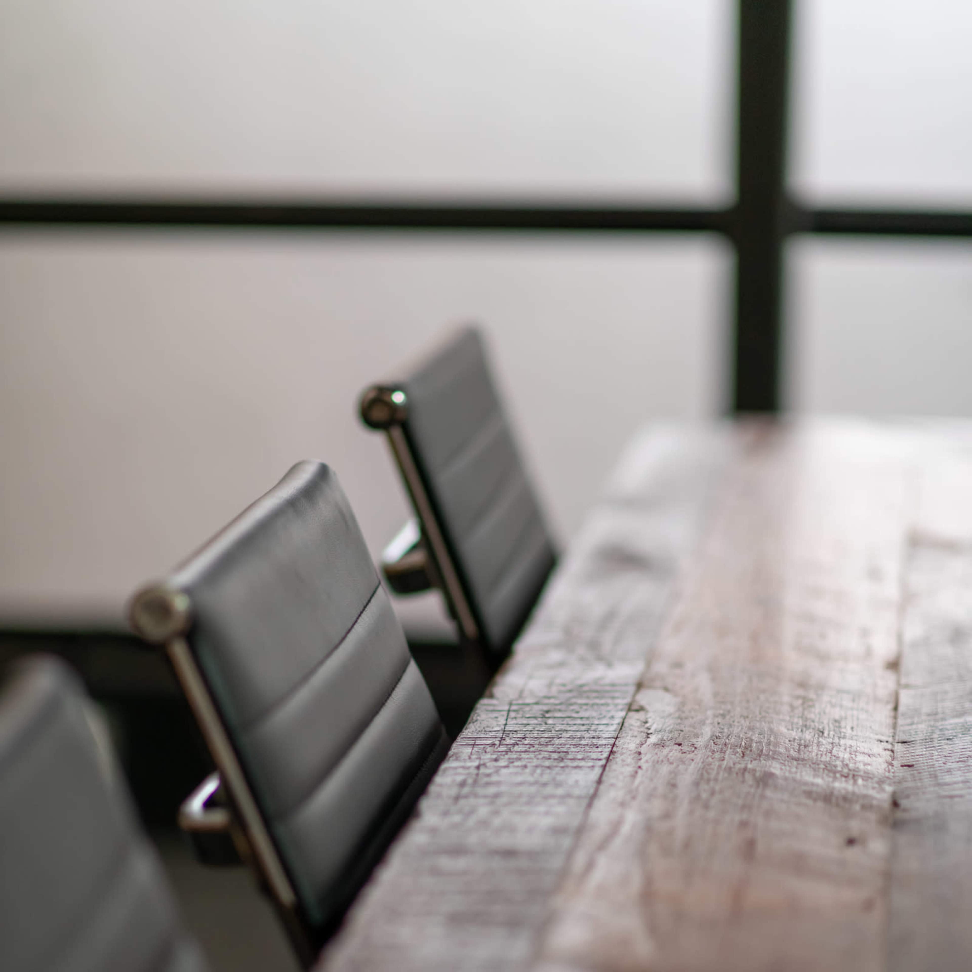 A wooden conference table is positioned in a room with two leather-backed chairs visible in the foreground.
