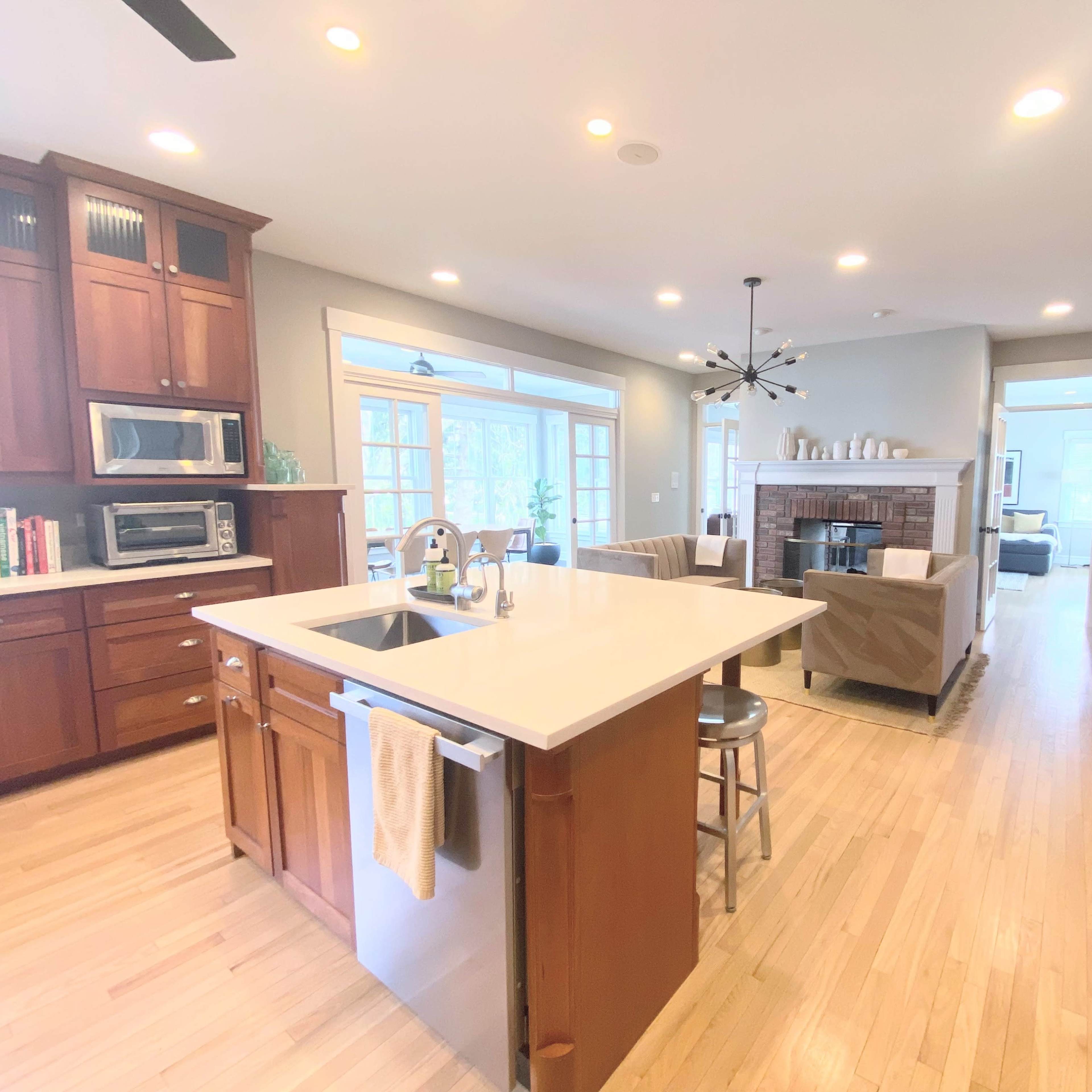 A spacious kitchen featuring wooden cabinetry, a central island with seating, and an open layout leading to a living area with a fireplace.