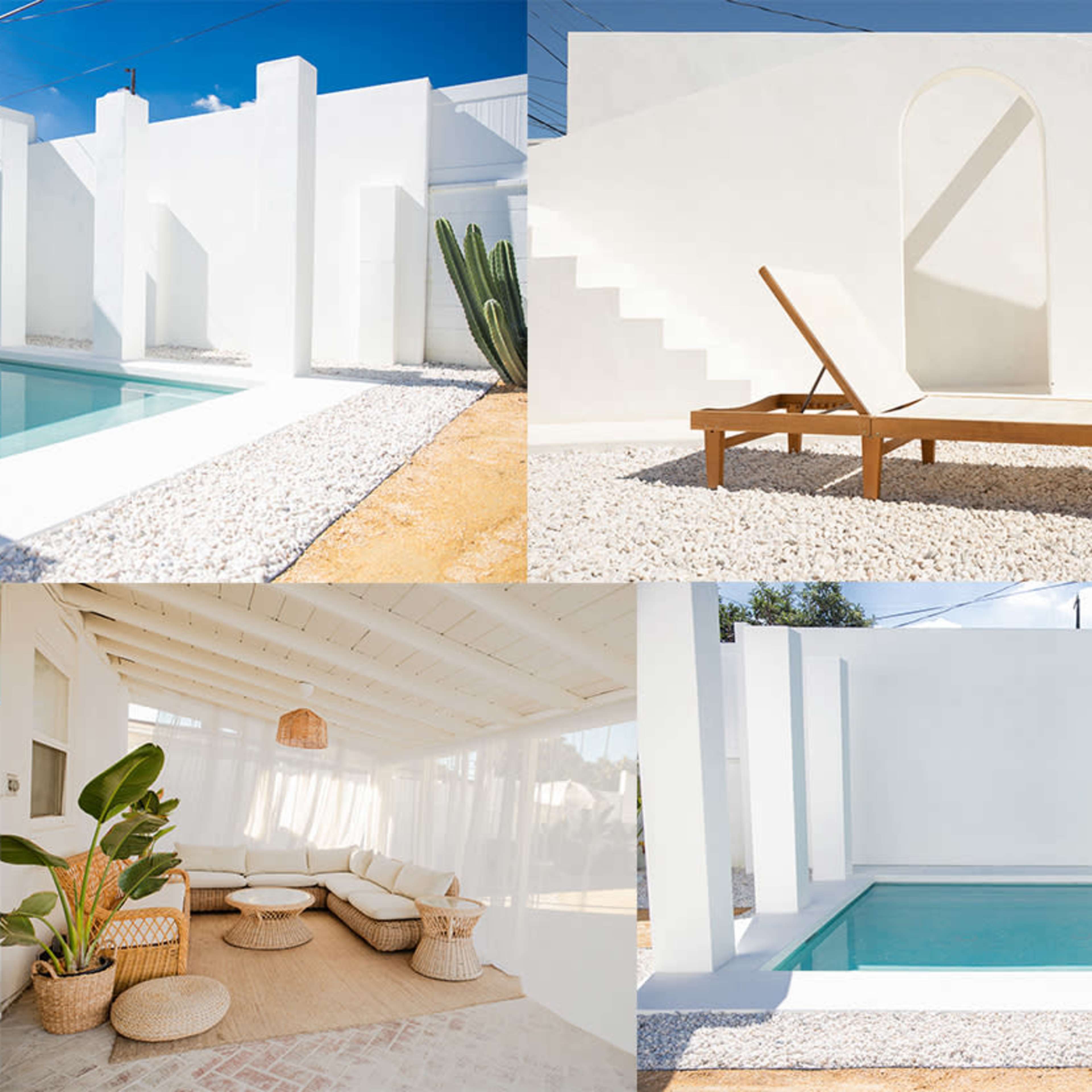 A minimalist outdoor space featuring a pool surrounded by white walls, a sun lounger, and a seating area with earthy decor.