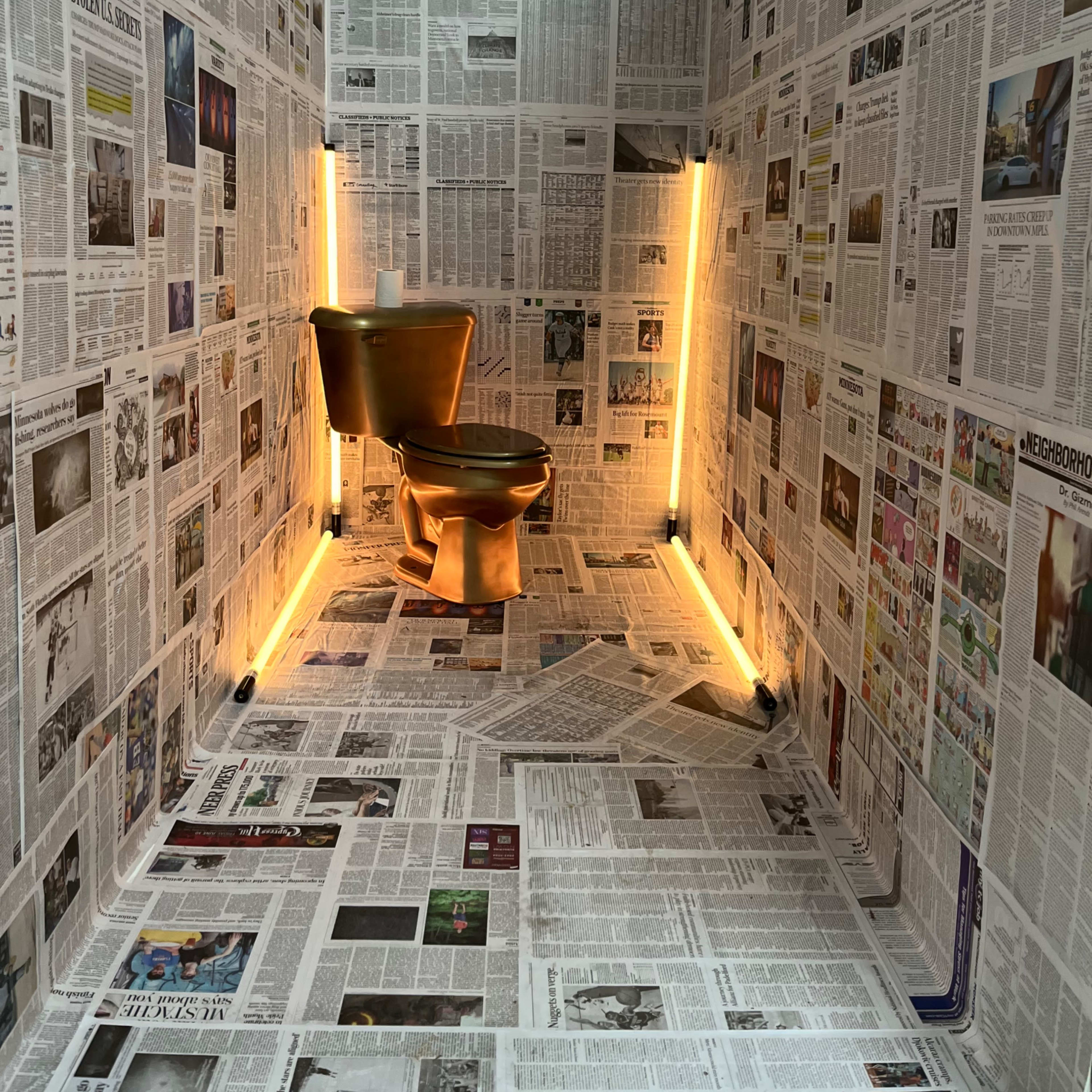 A small room entirely covered in newspapers, featuring a gold-colored toilet centered against a backdrop of newsprint with ambient lighting along the walls.