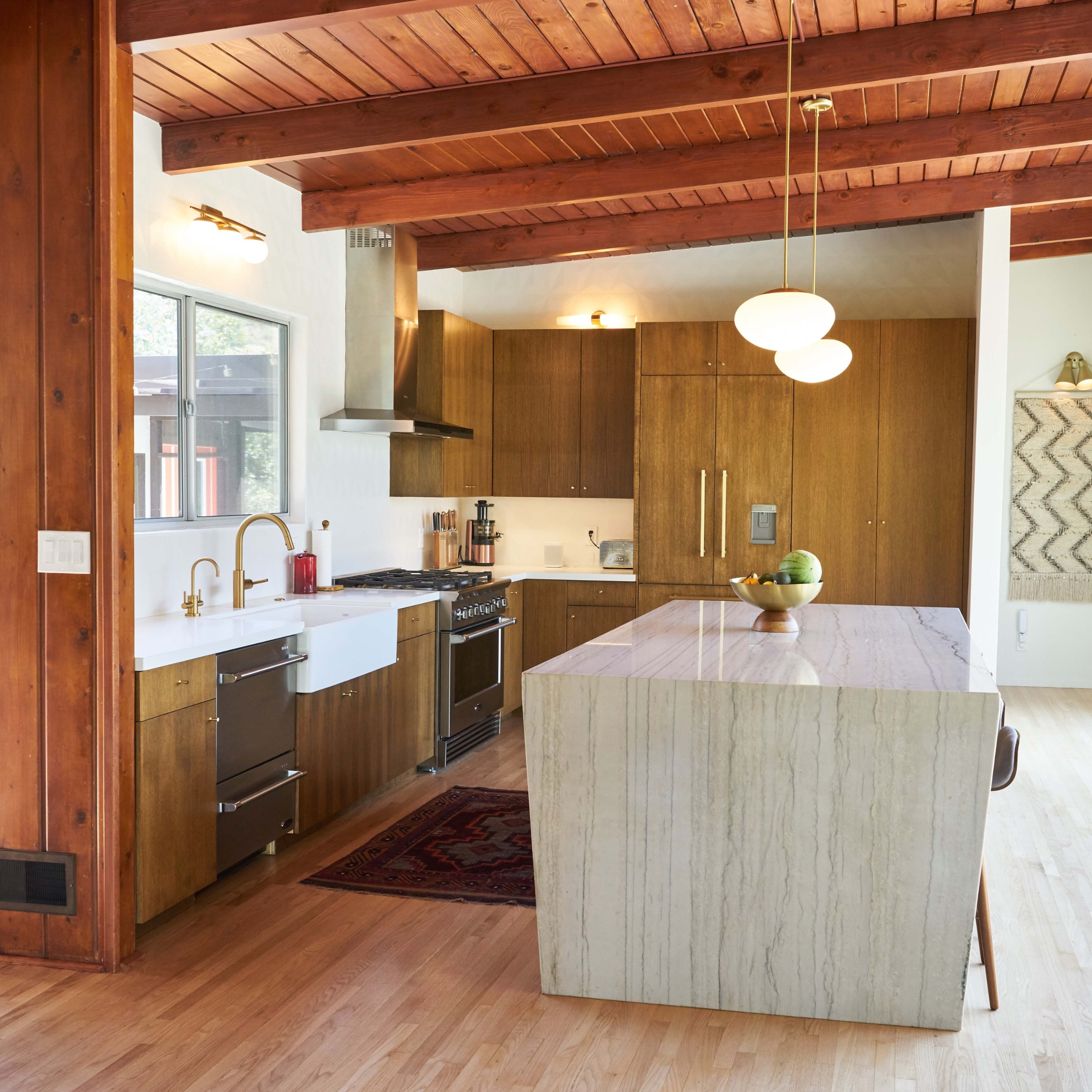 A modern kitchen with wooden beams, a marble-topped island, and contemporary appliances.