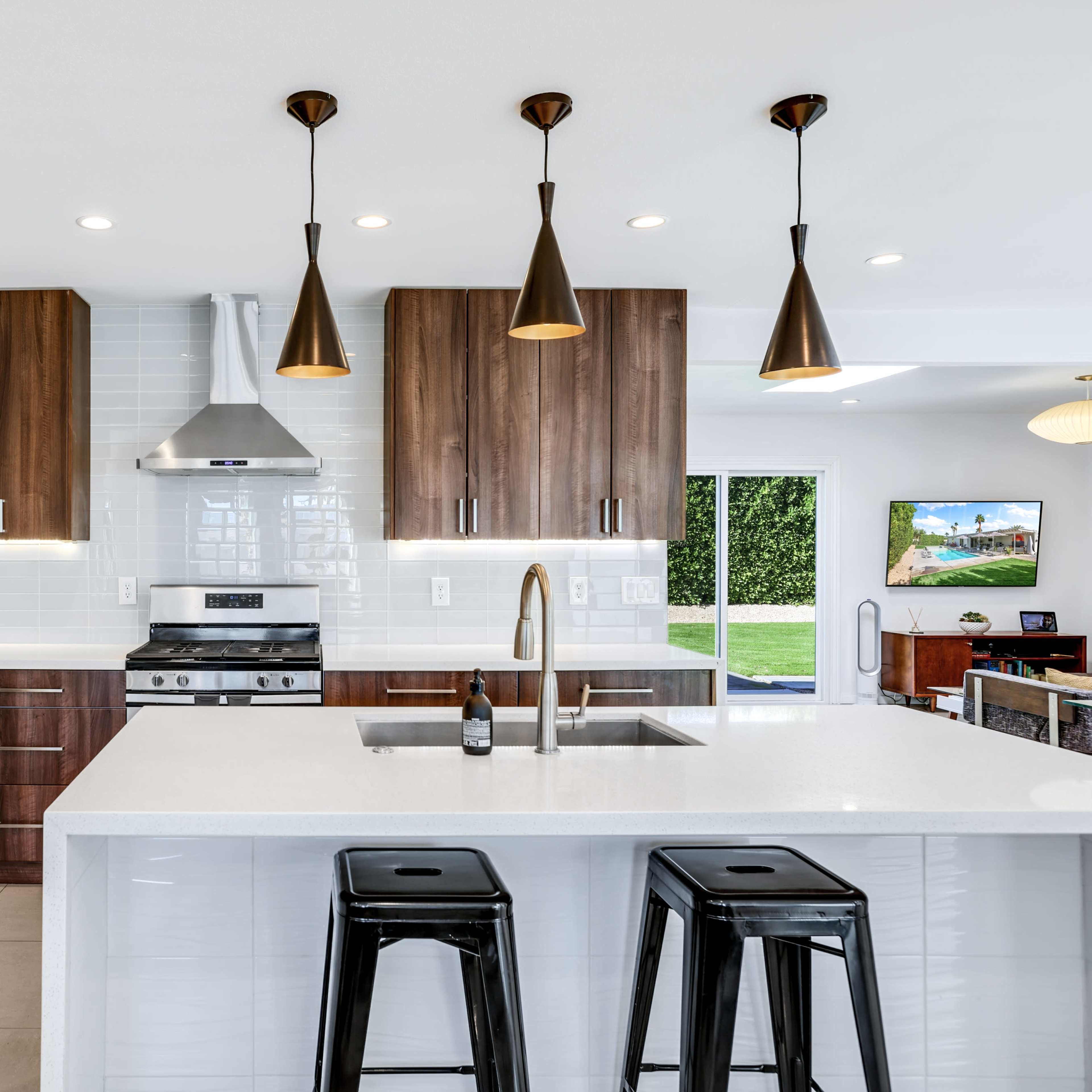 A modern kitchen with dark wood cabinets, stainless steel appliances, and a central island with black bar stools.