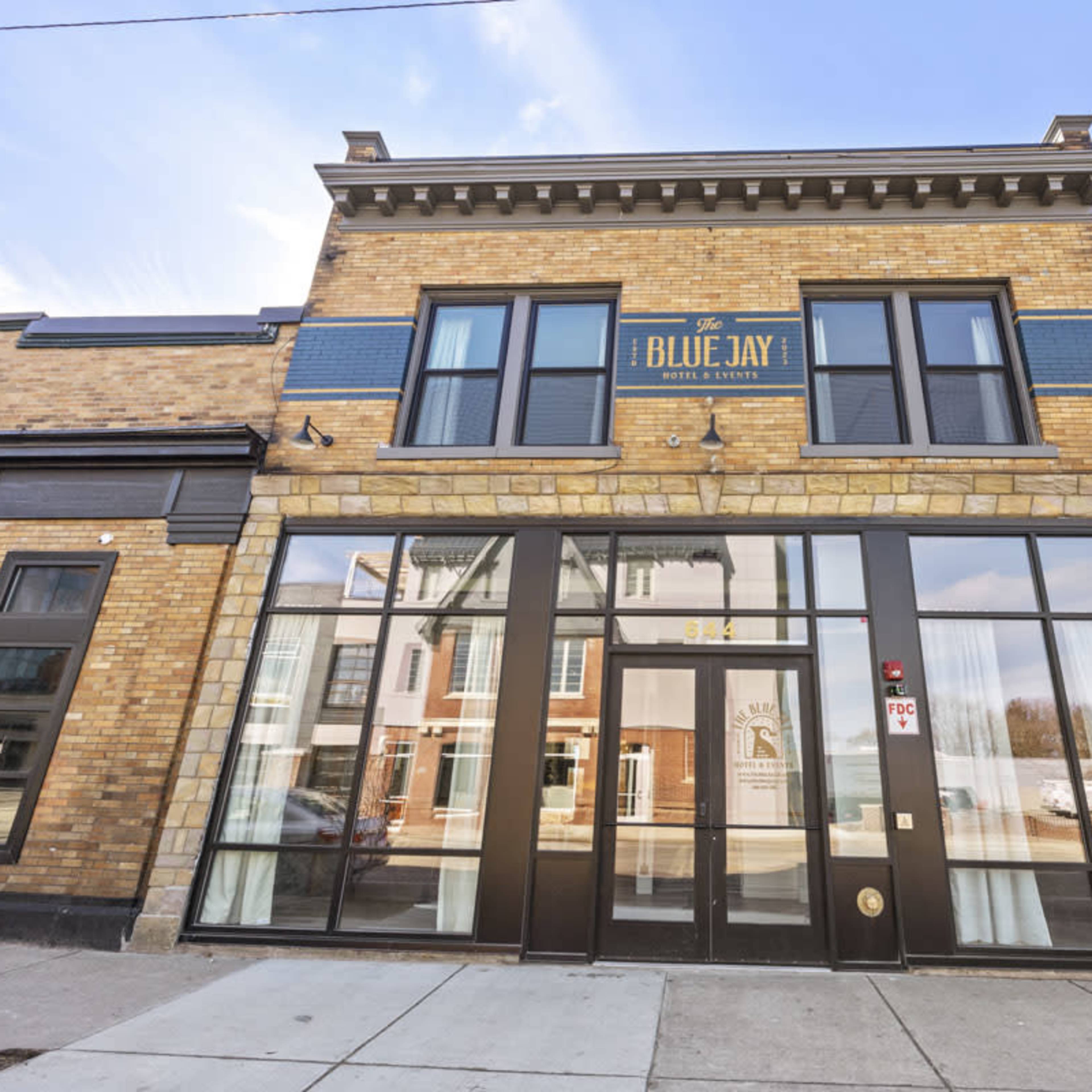The front facade of a brick building with large windows and a sign reading "The Blue Jay!" above the entrance.