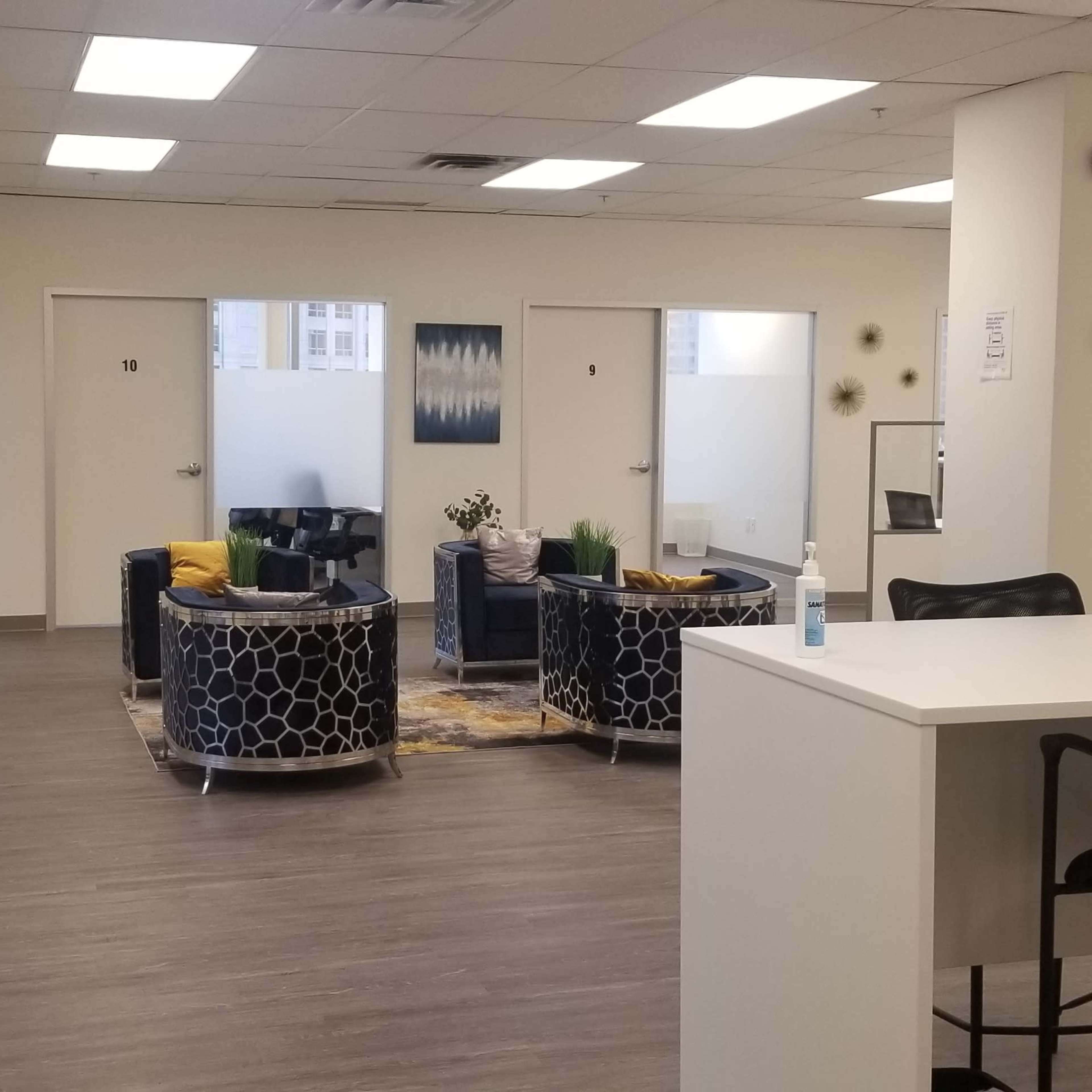 A modern office space with seating areas, several closed office doors, and a reception-style counter.