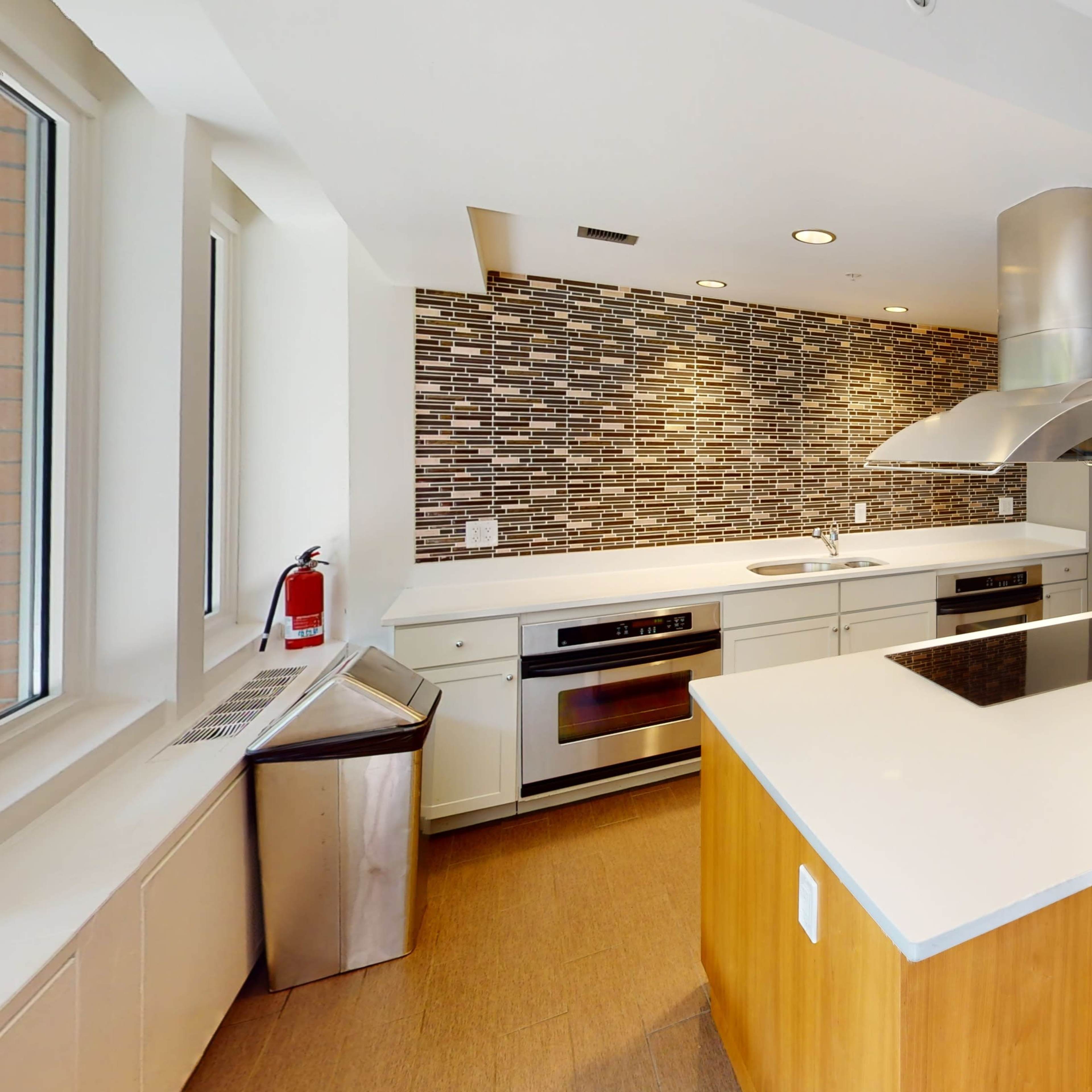 A modern kitchen with an island, stainless steel appliances, and a tiled backsplash.