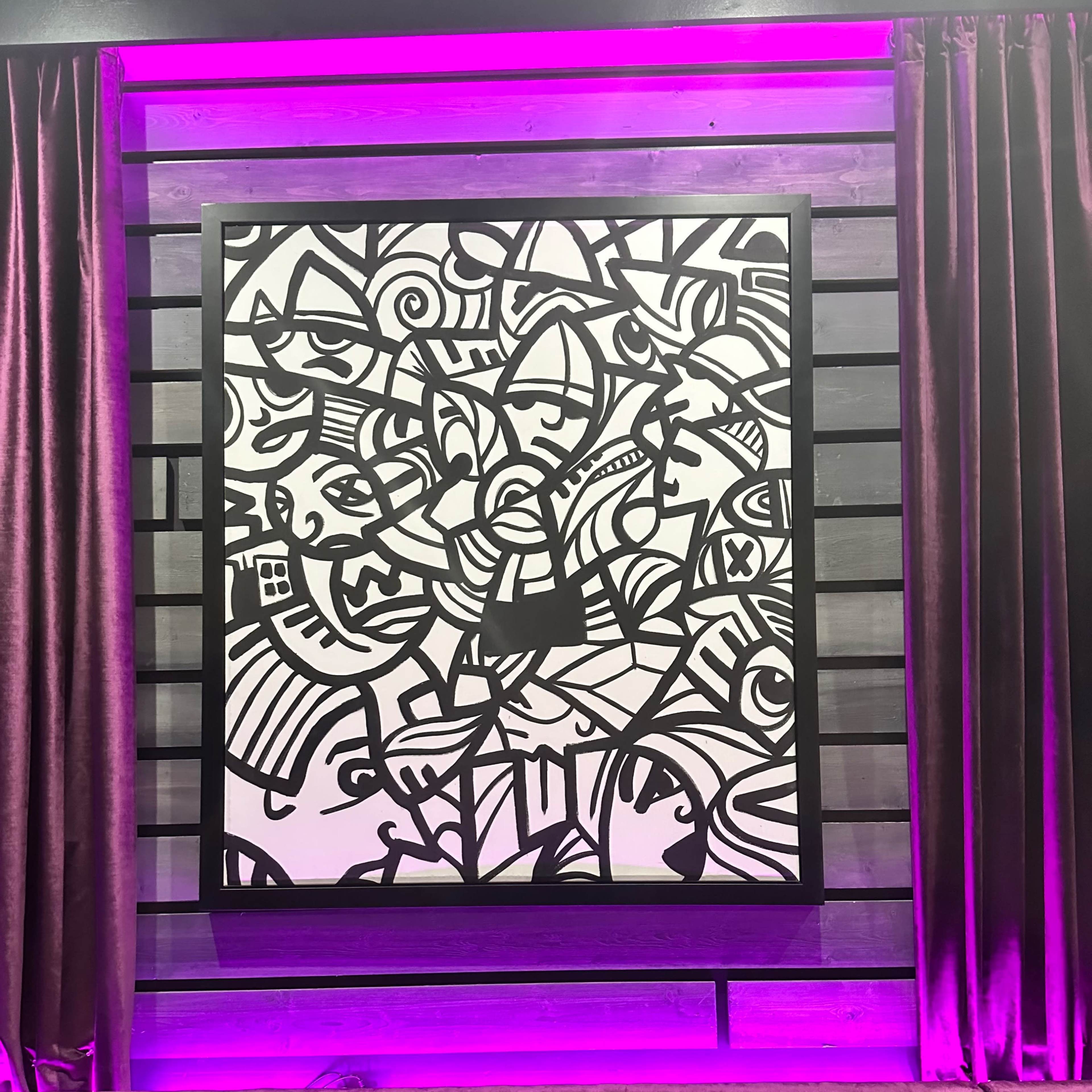 A large black and white abstract art piece, densely filled with various shapes and lines, positioned on a wall with purple lighting and velvet curtains.