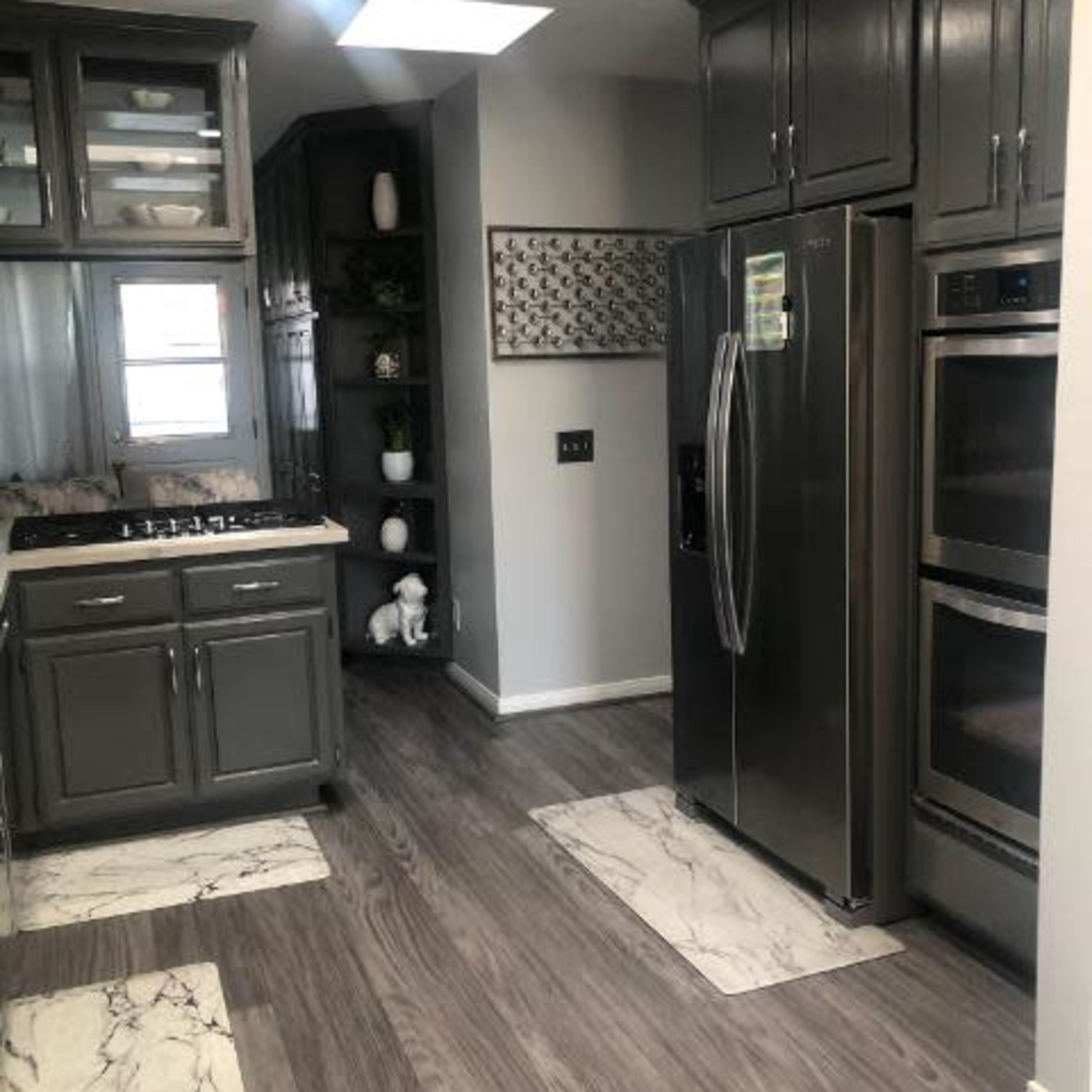A modern kitchen featuring gray cabinets, stainless steel appliances, and marble-patterned floor mats.