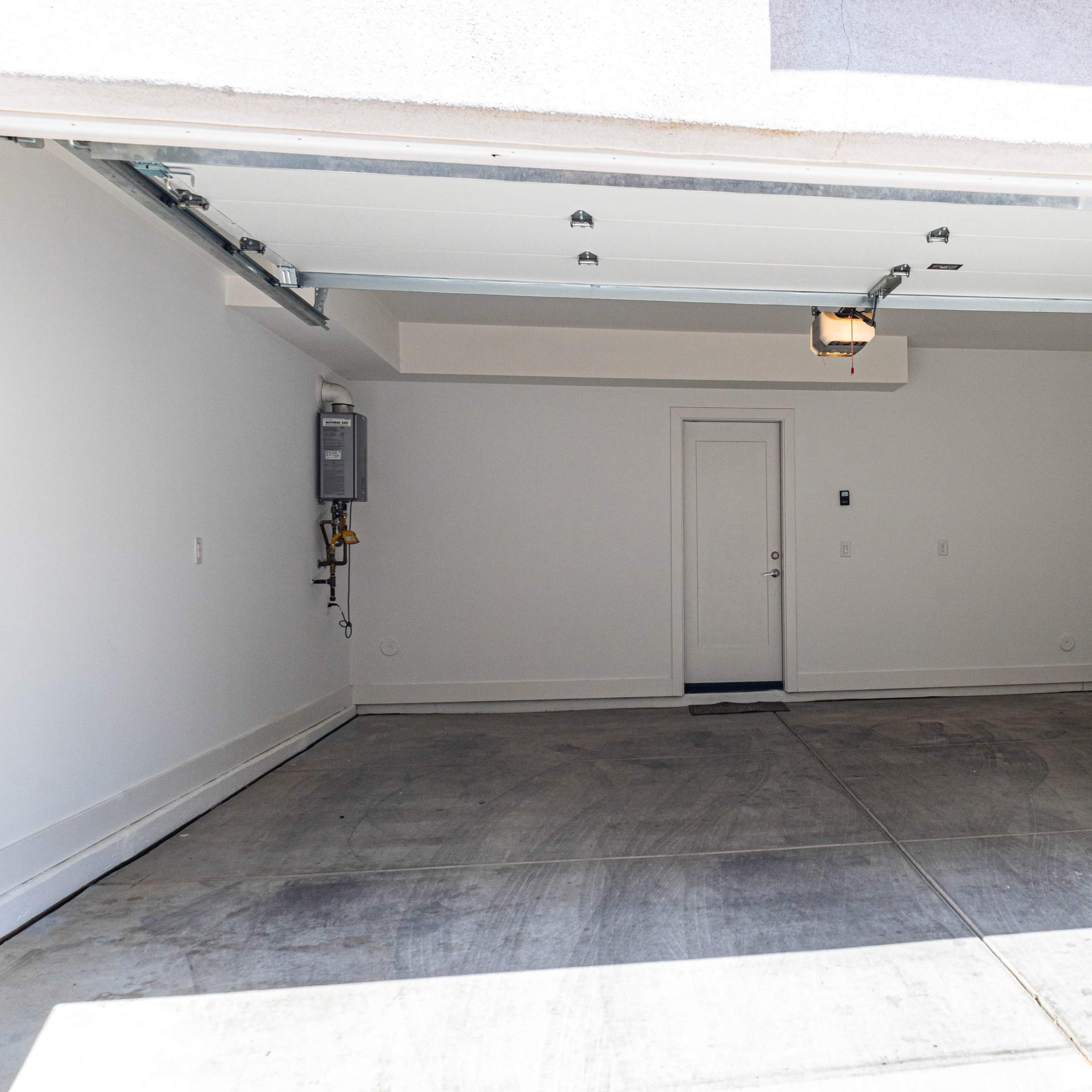 An empty garage with concrete flooring and a closed door.