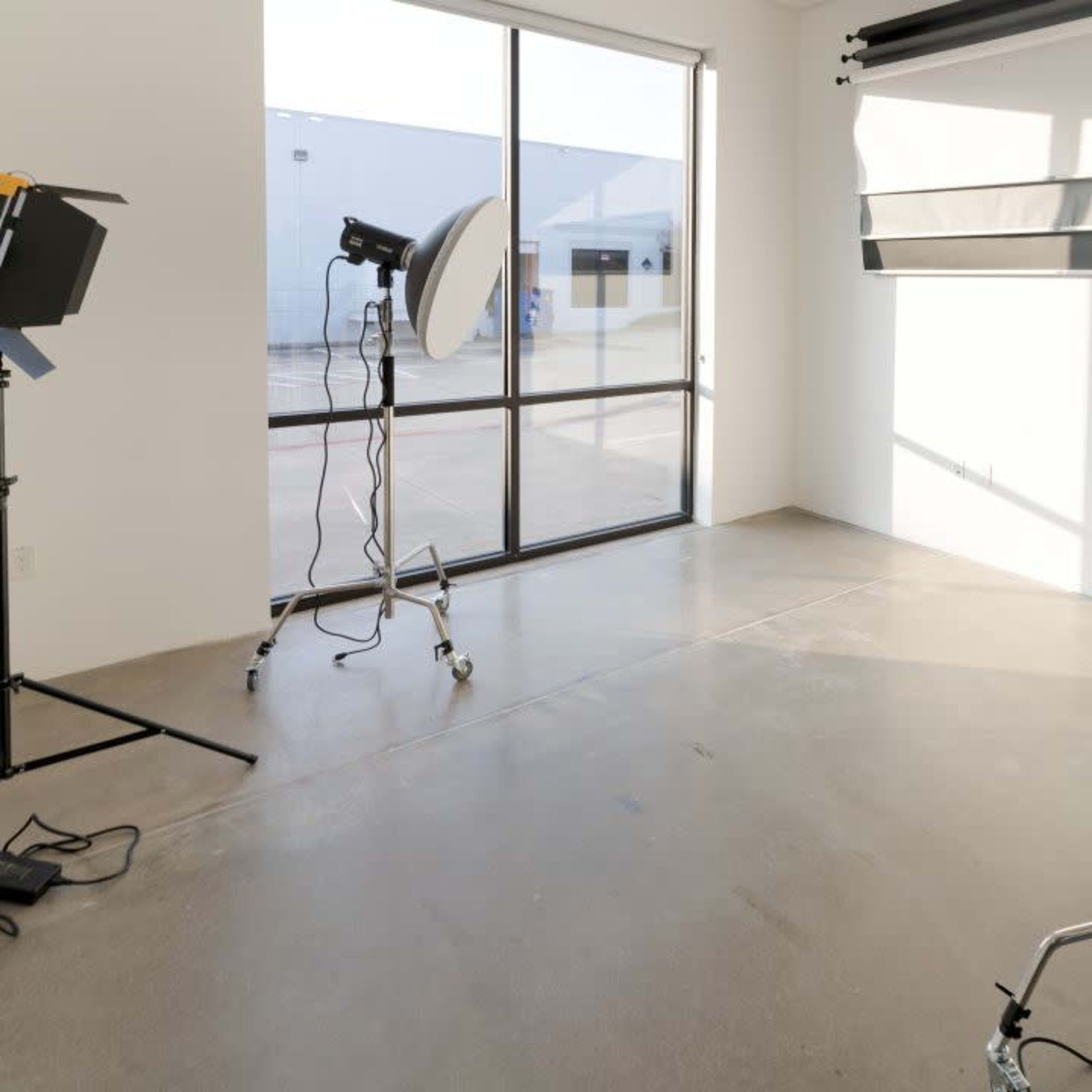 A well-lit photography studio with soft lighting equipment and a large window.