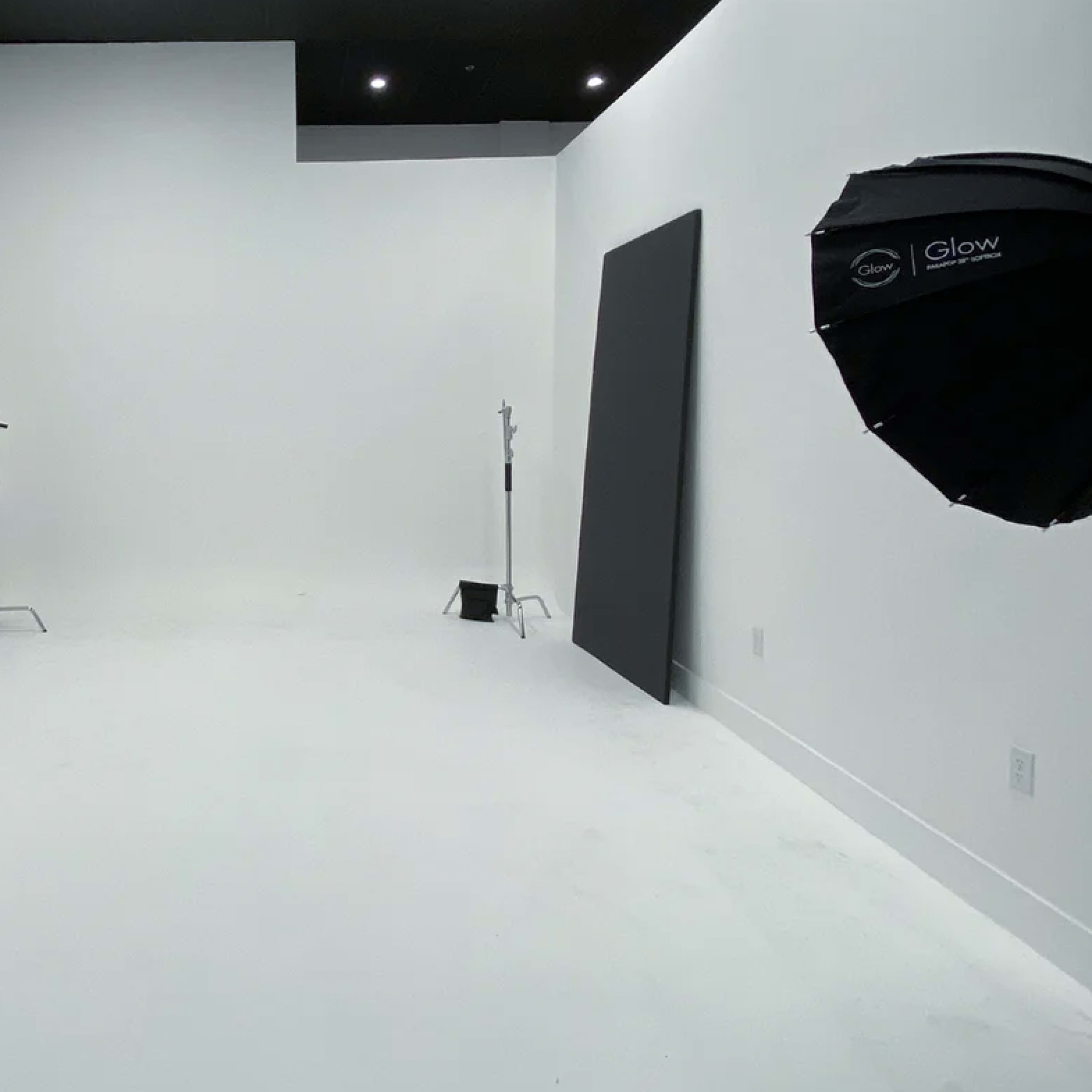 A spacious photography studio with white walls and two lighting setups on either side.