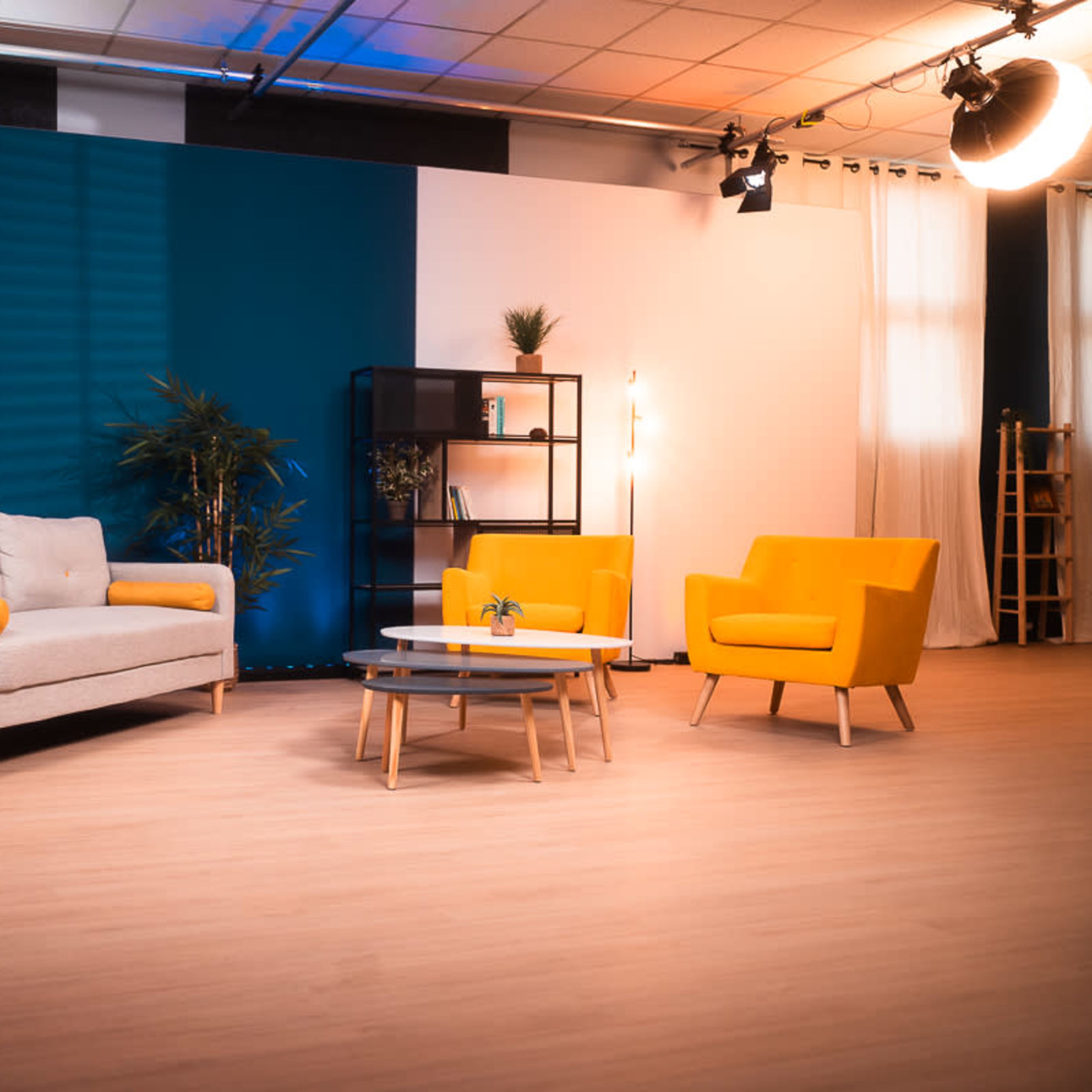 A modern interior design setup with a gray sofa, two yellow armchairs, a coffee table, and shelving units against a backdrop of blue and white walls.