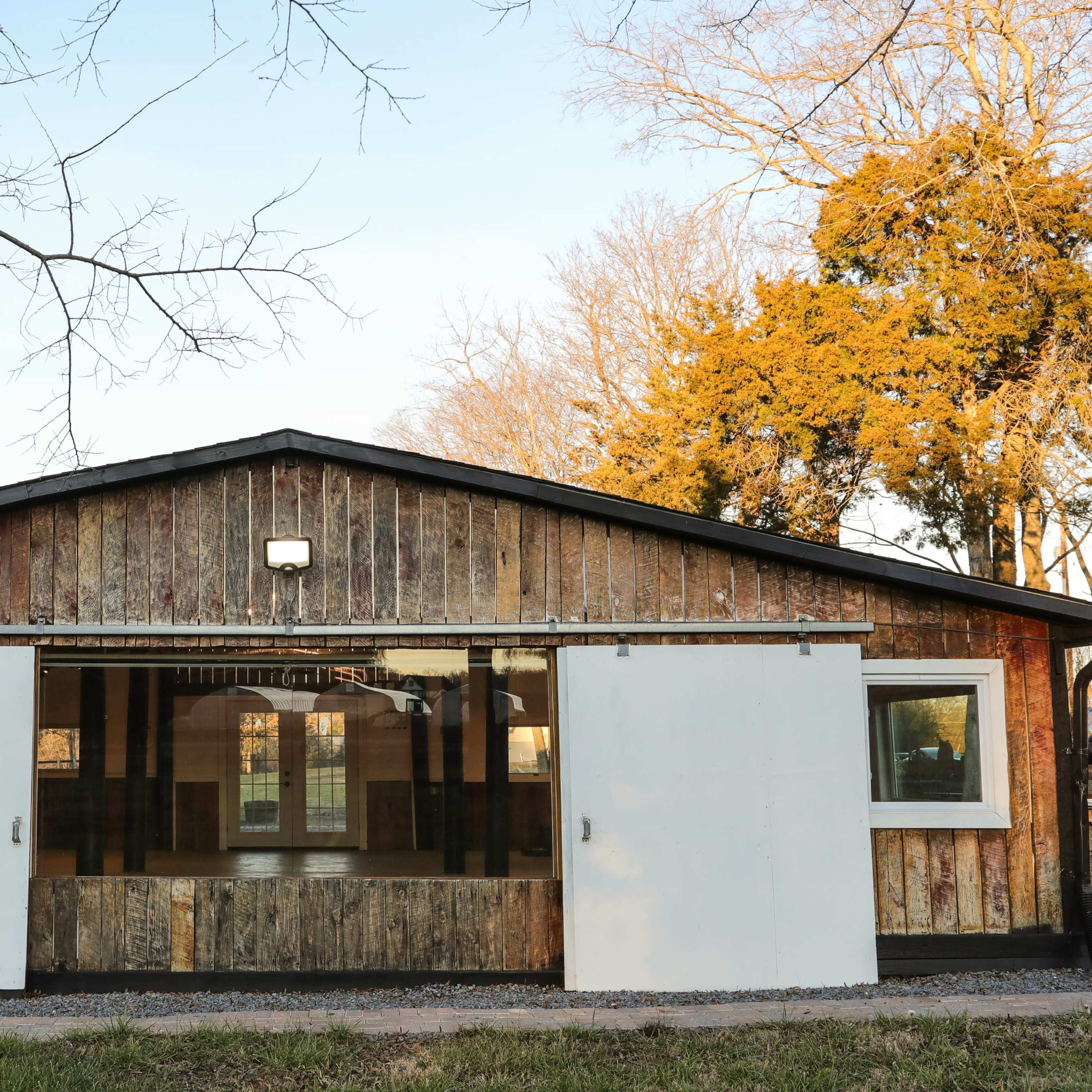 A rustic wooden building with sliding white doors and large windows.