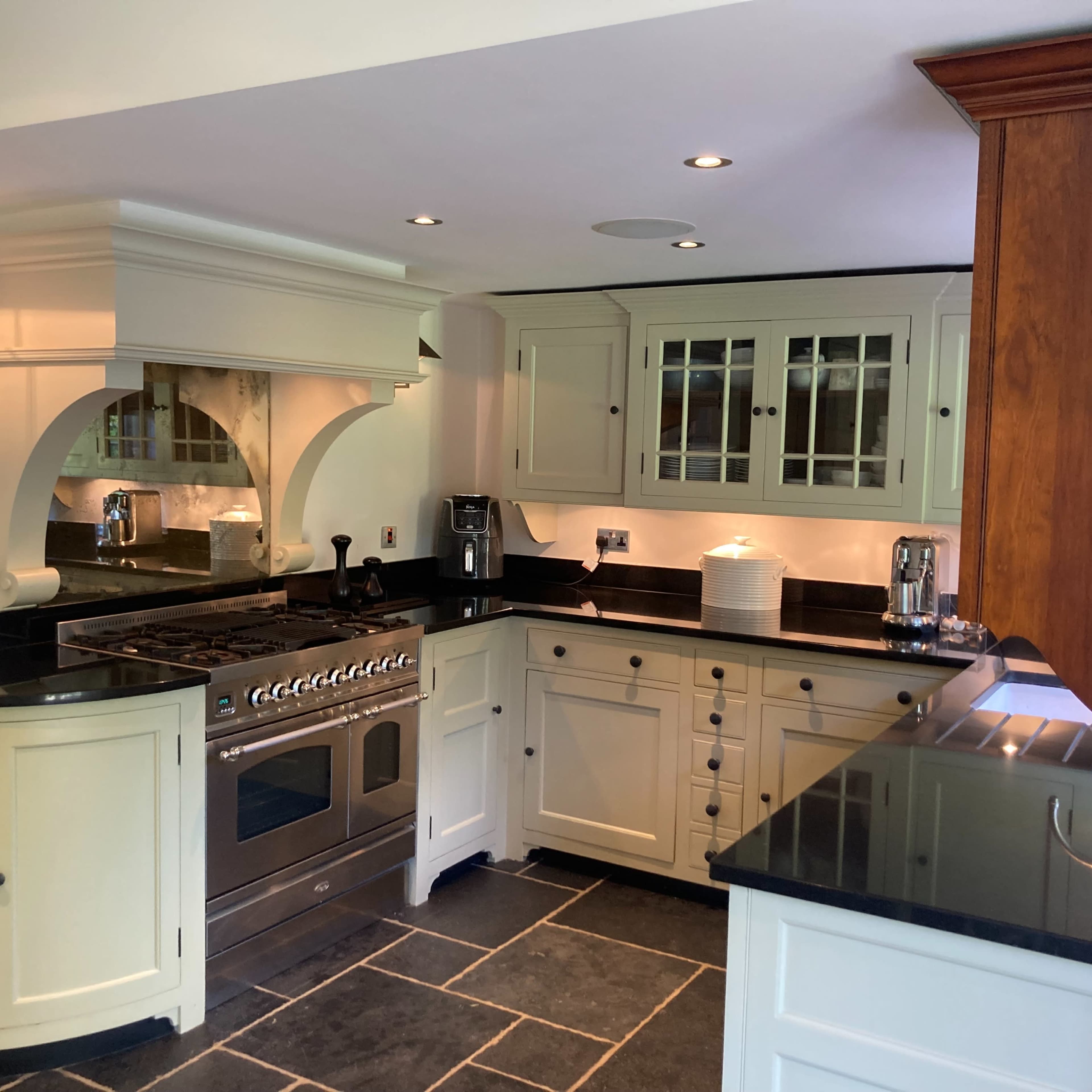 The kitchen features white cabinetry, a stainless steel range, dark countertops, and slate flooring.