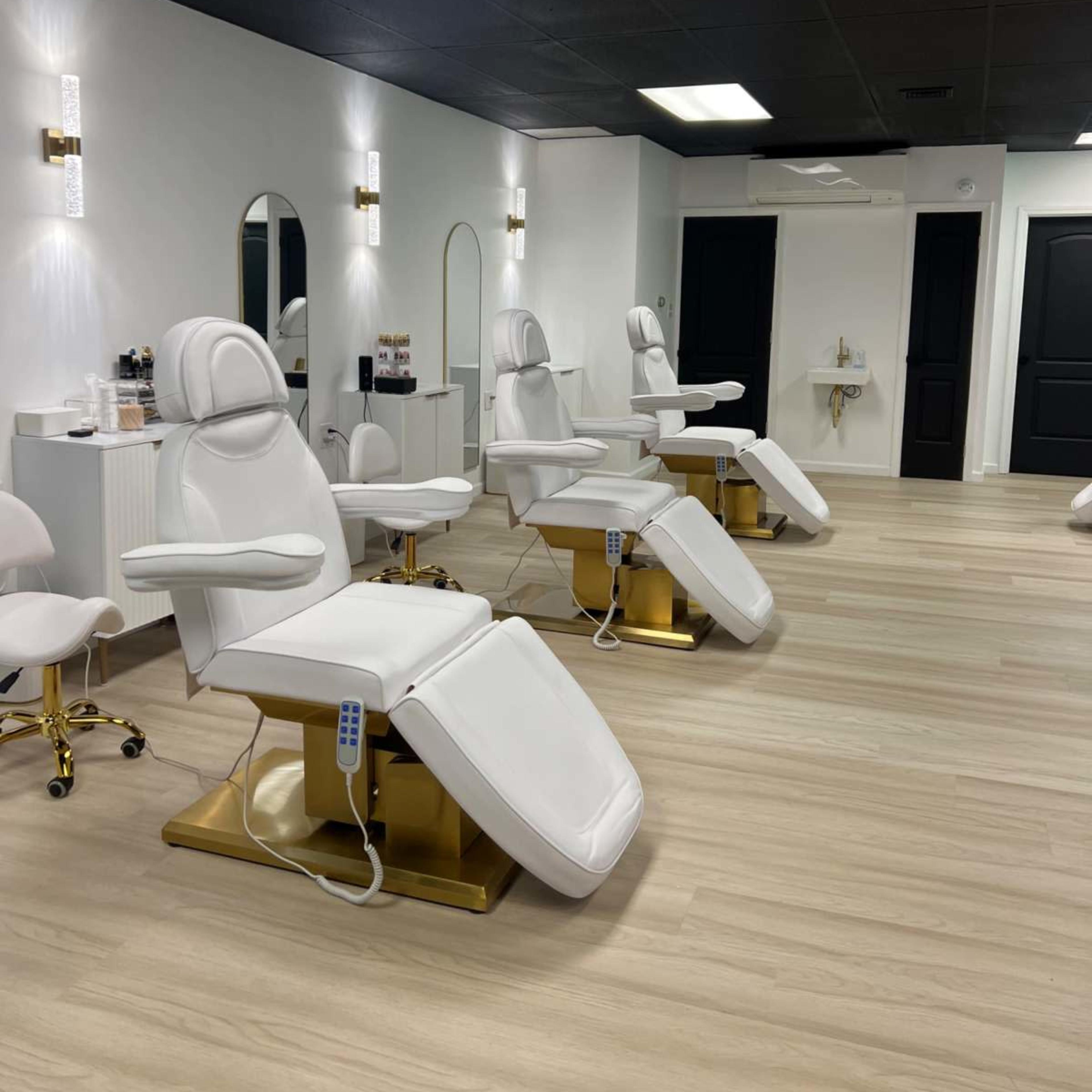 A modern salon interior with several white treatment chairs arranged neatly on a light wood floor.