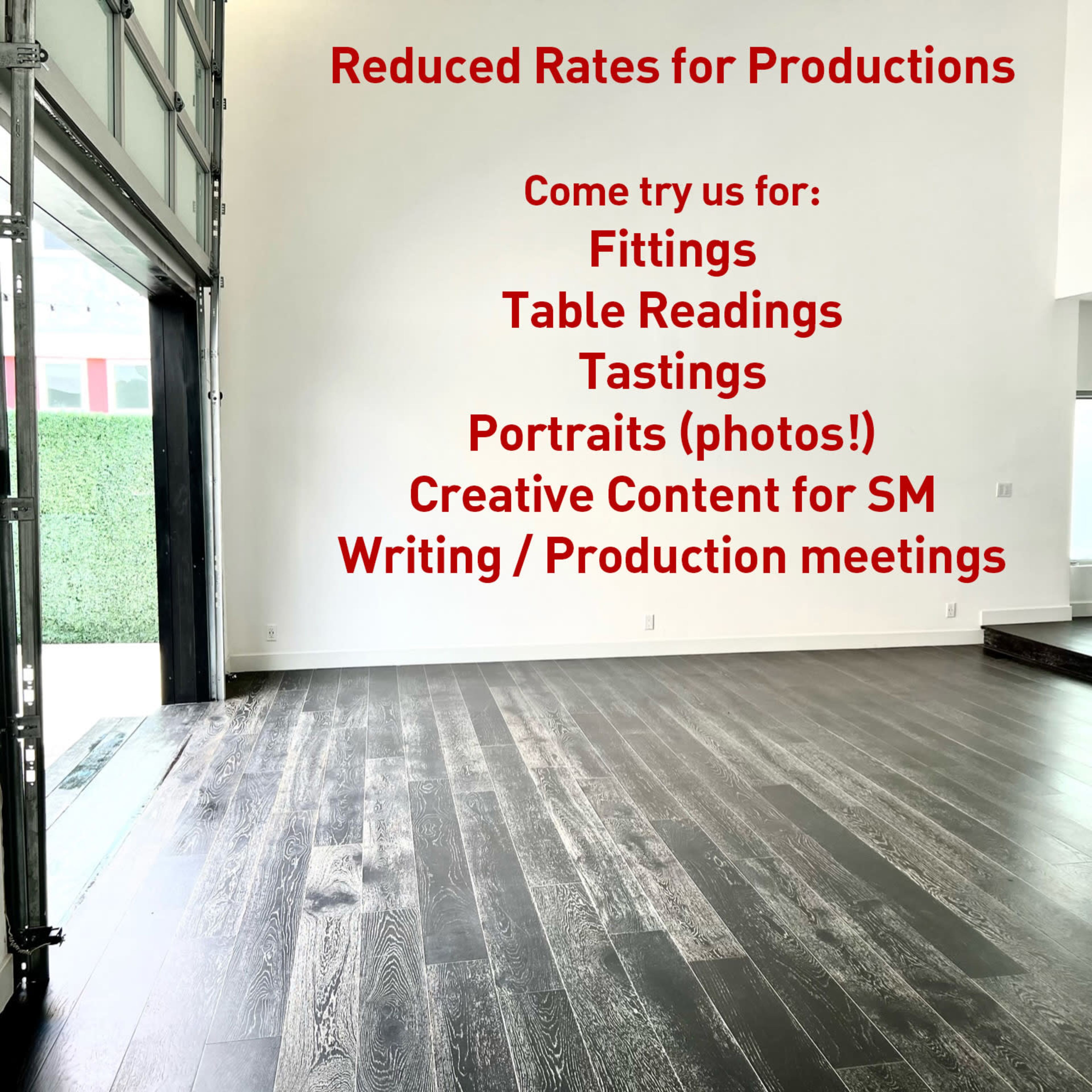 A spacious, empty room with hardwood flooring and a large wall featuring red text advertising reduced rates for various production services.
