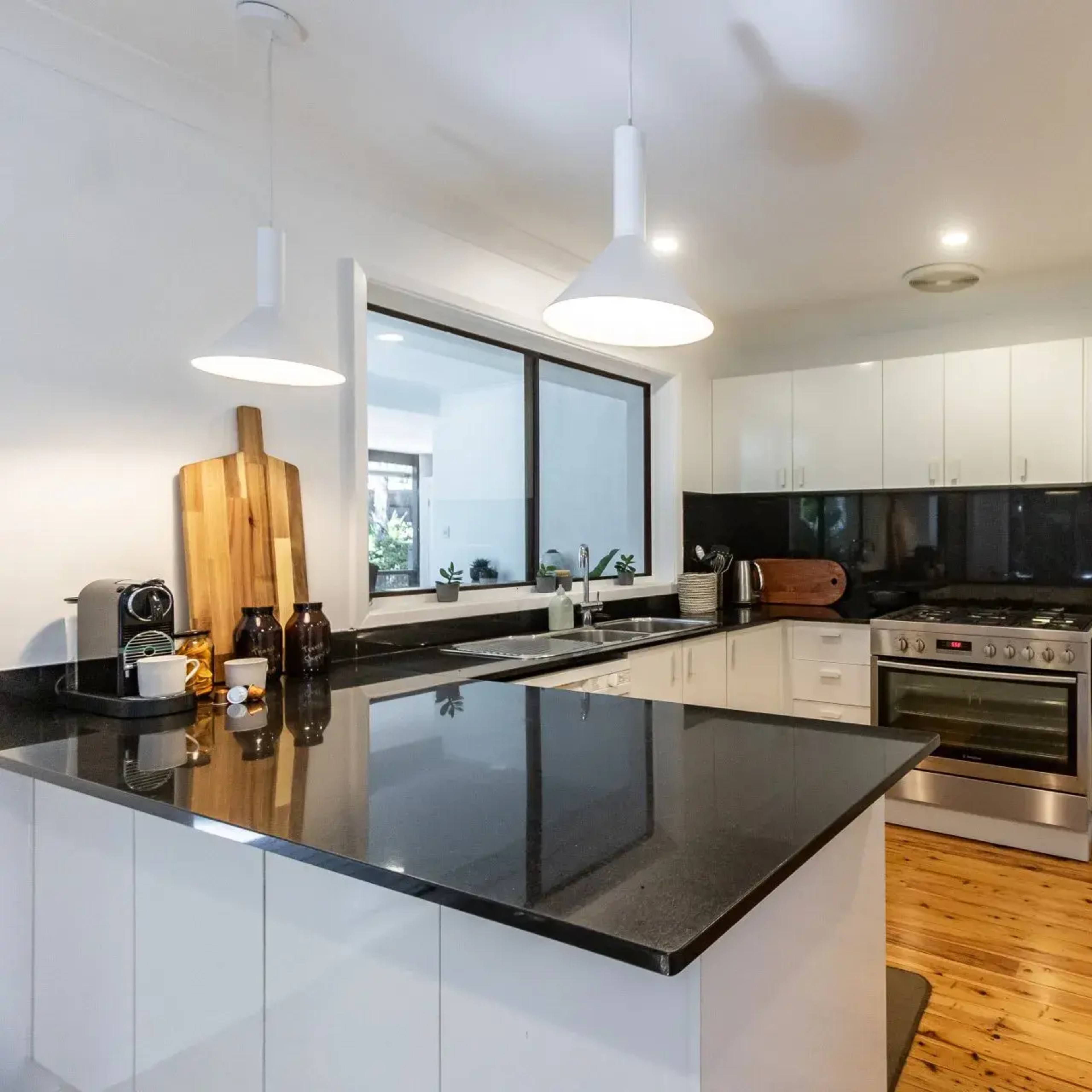 A modern kitchen features white cabinetry, a black countertop, and stainless steel appliances.