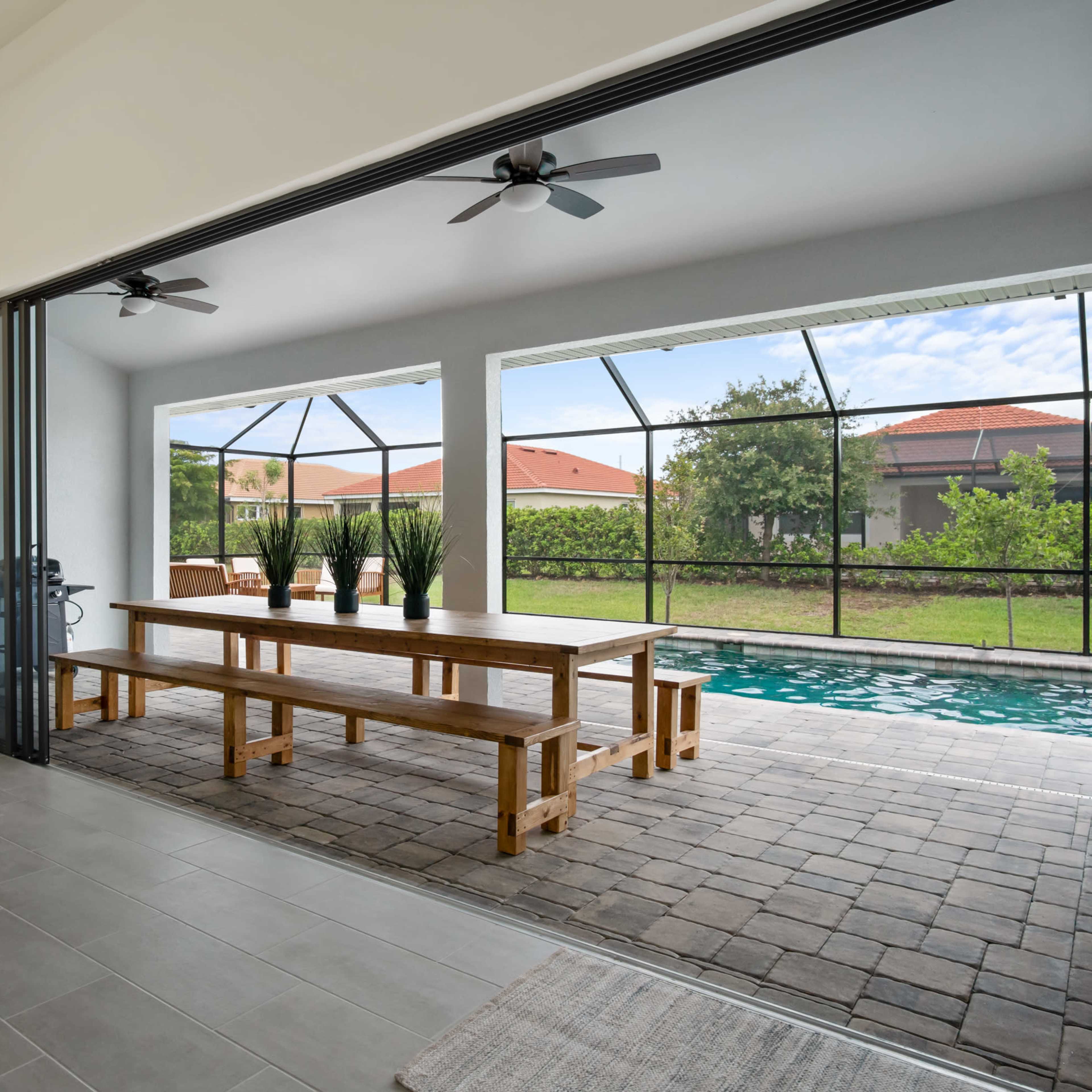 A modern living space with a large sliding glass door that opens to a patio with a swimming pool and outdoor seating area.