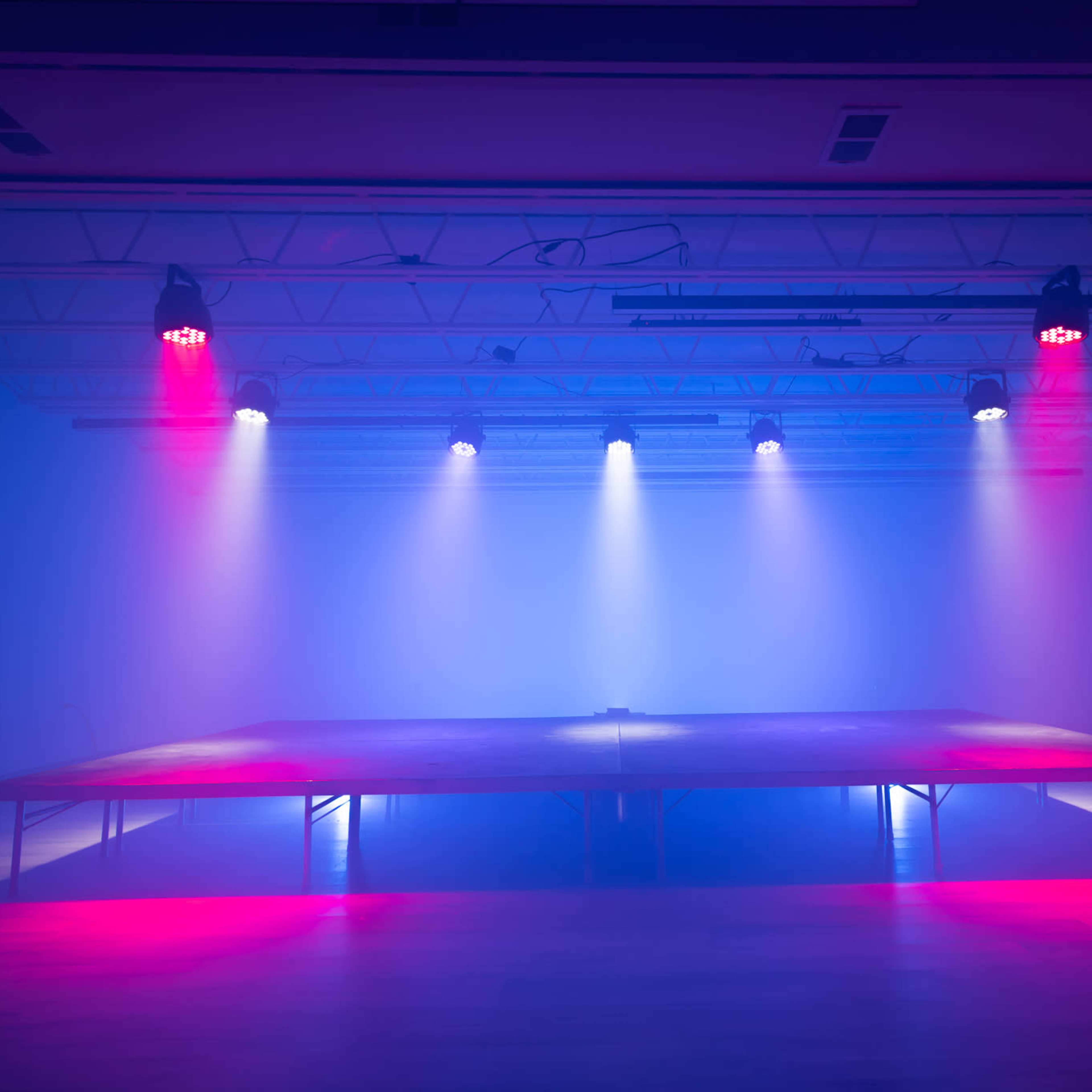 A stage is illuminated by various colored lights in a dimly lit room.