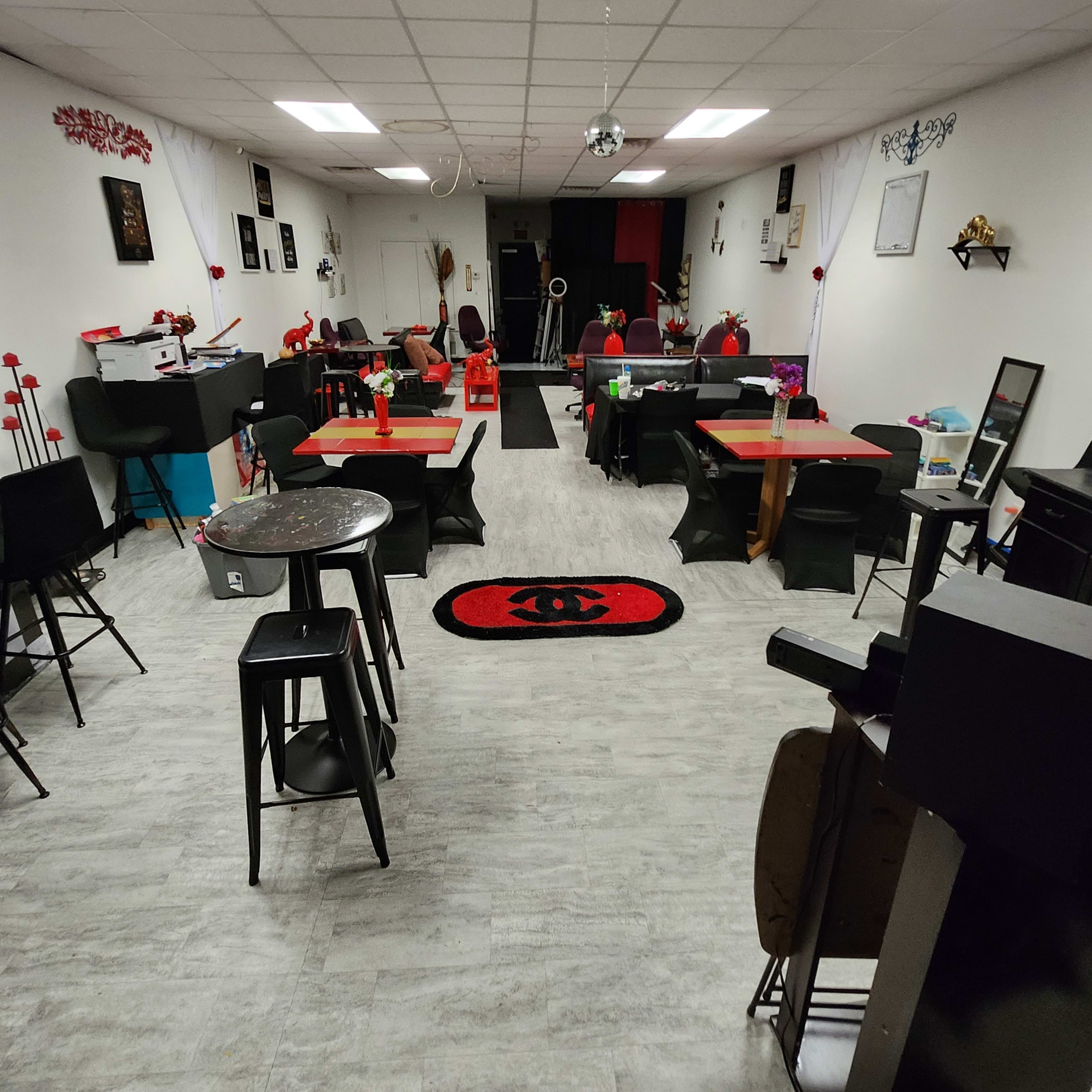 An indoor space set up with tables and chairs, decorated with red accents and a mirrored disco ball hanging from the ceiling.