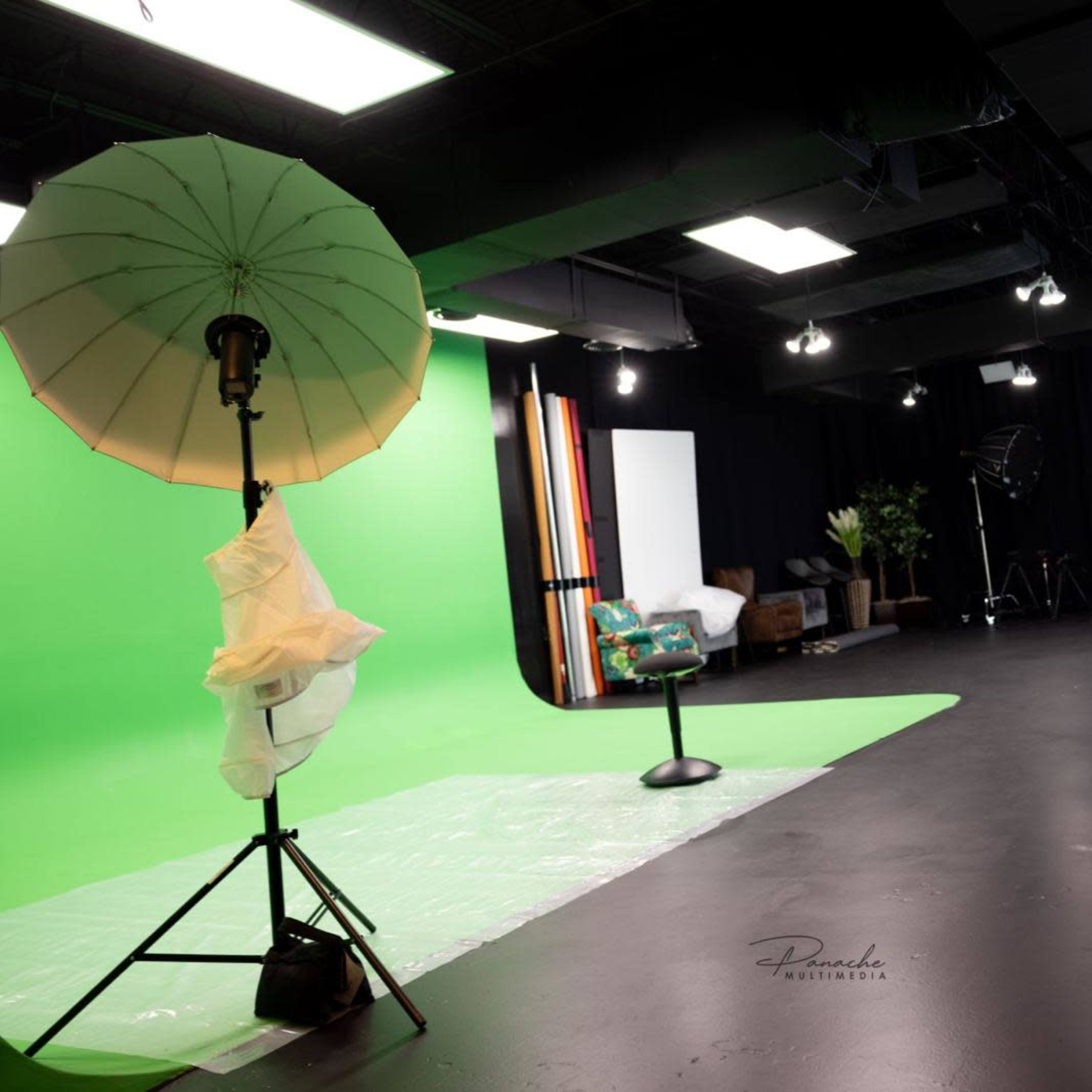 A photography studio equipped with green and white backdrops, lighting setups, and various props.
