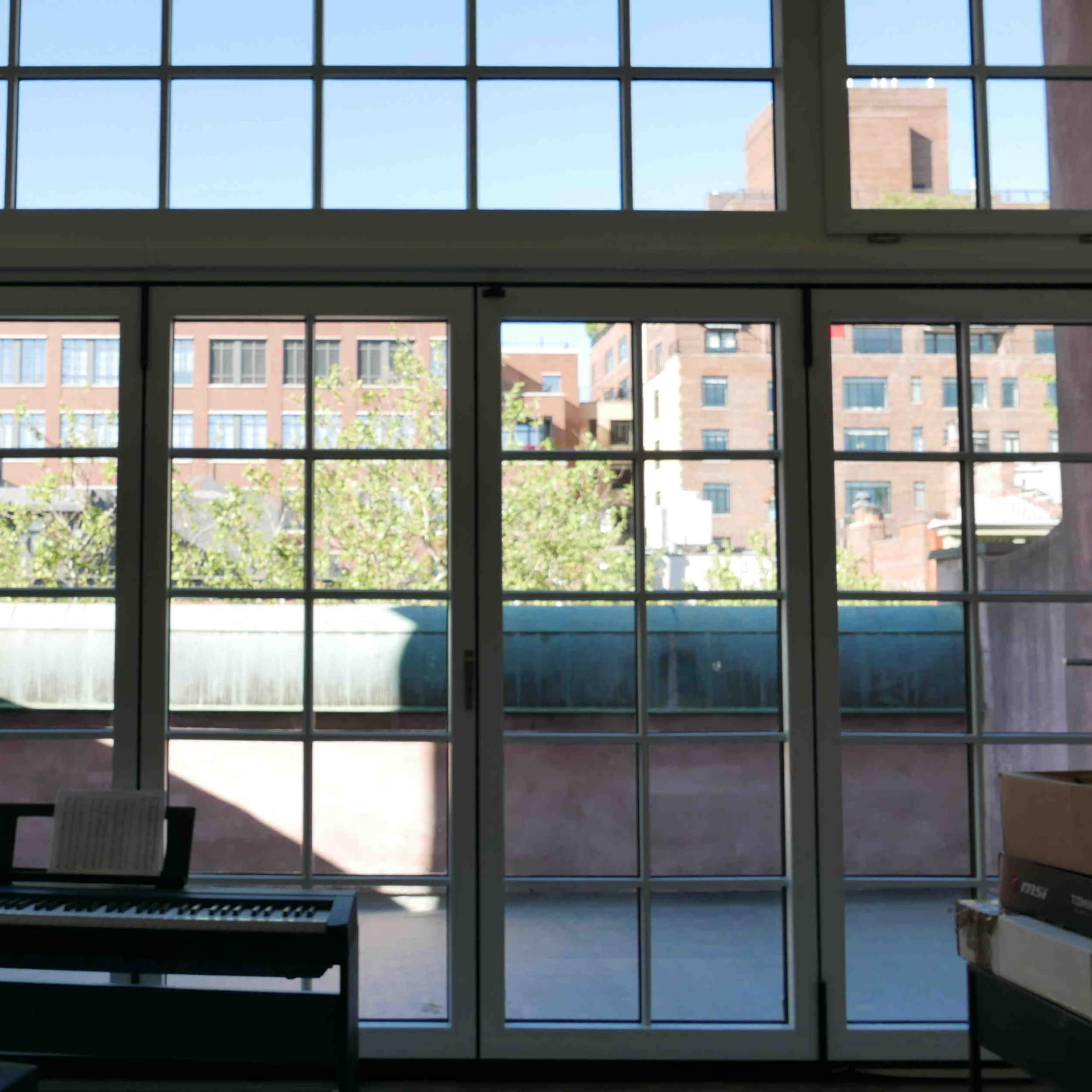 A large window with multiple panes, revealing an urban view of buildings and greenery outside, with a keyboard positioned in the foreground.