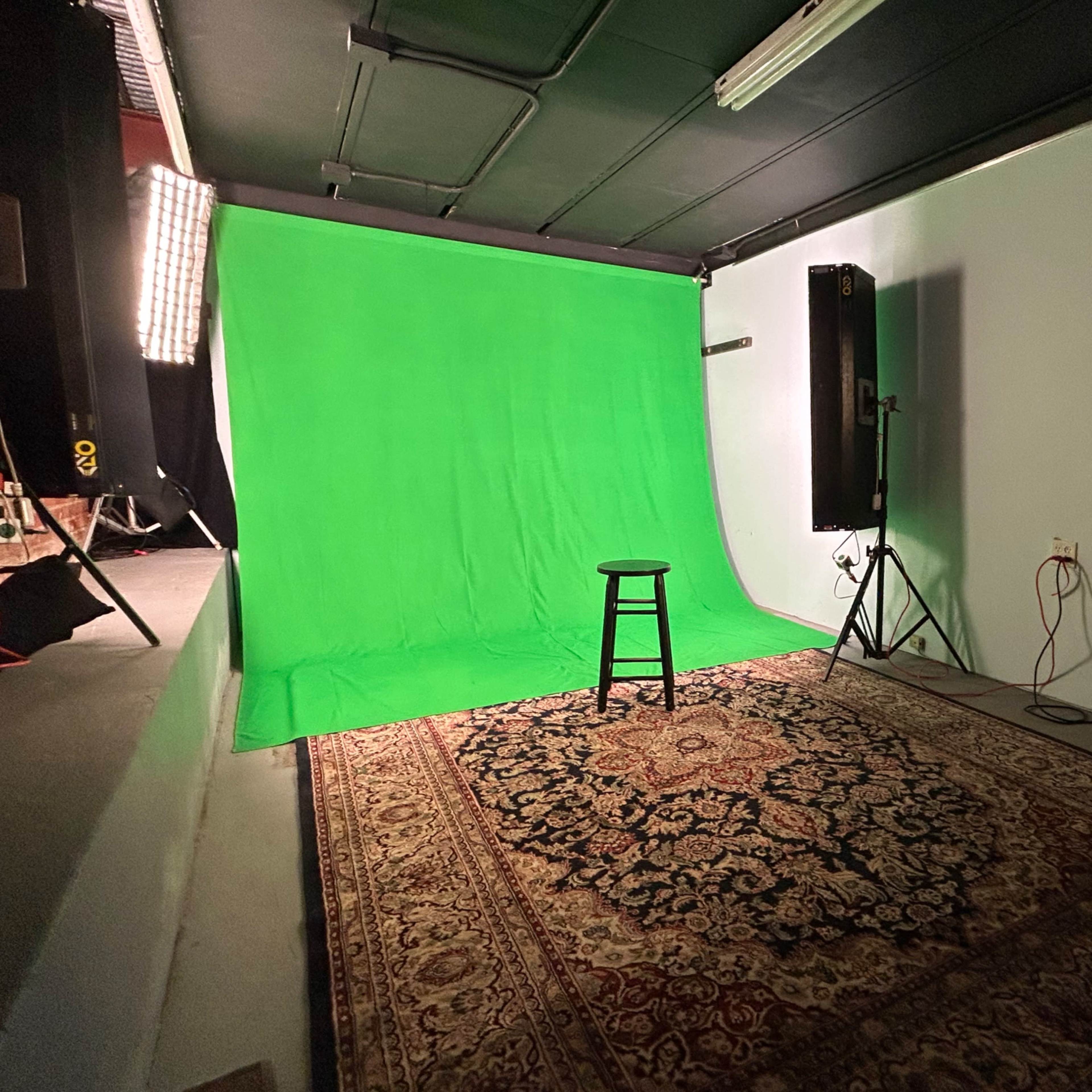 A green screen studio setup featuring a stool on a patterned rug, with lighting equipment on either side.