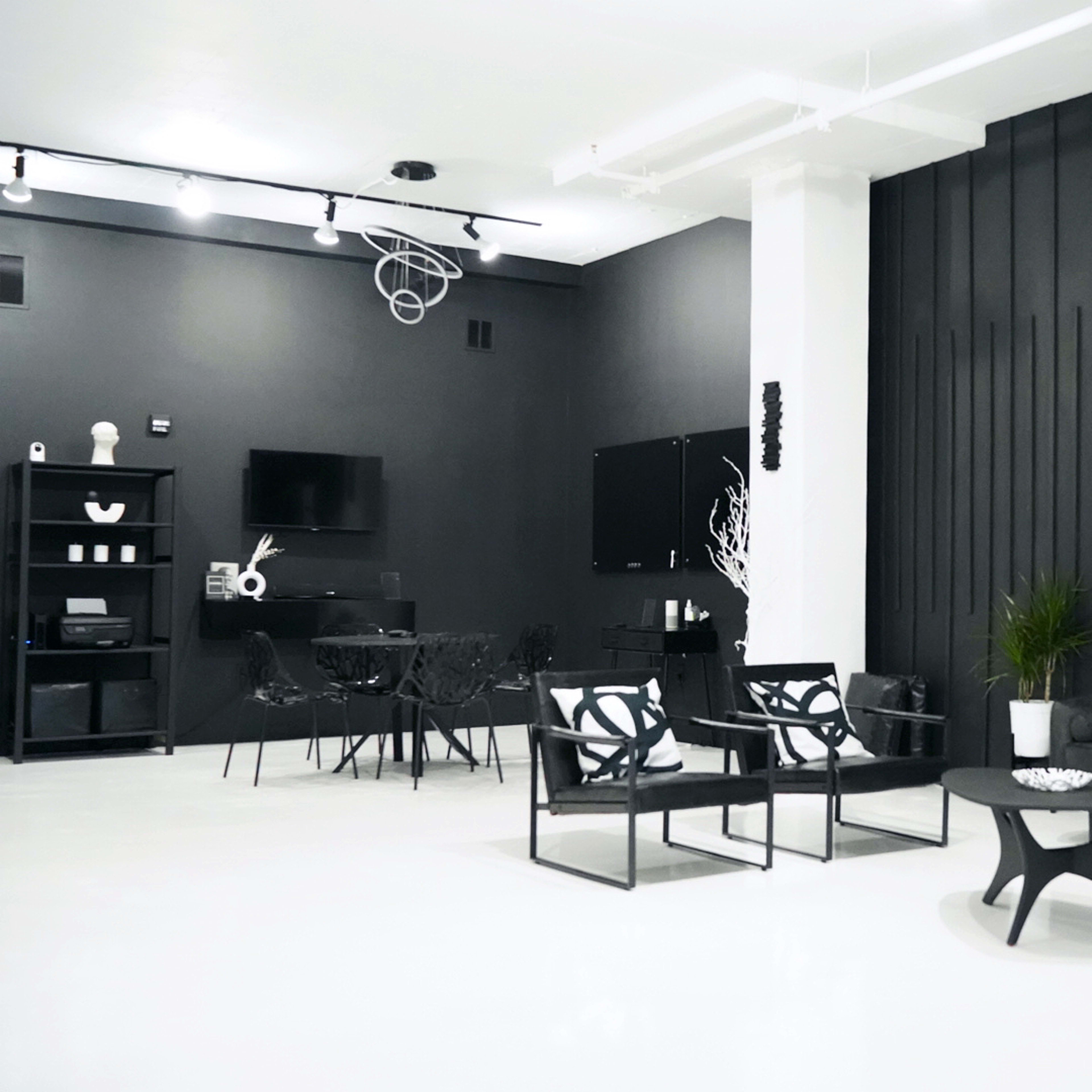 A modern room with black walls, white flooring, minimalist furniture, and a sleek design aesthetic.