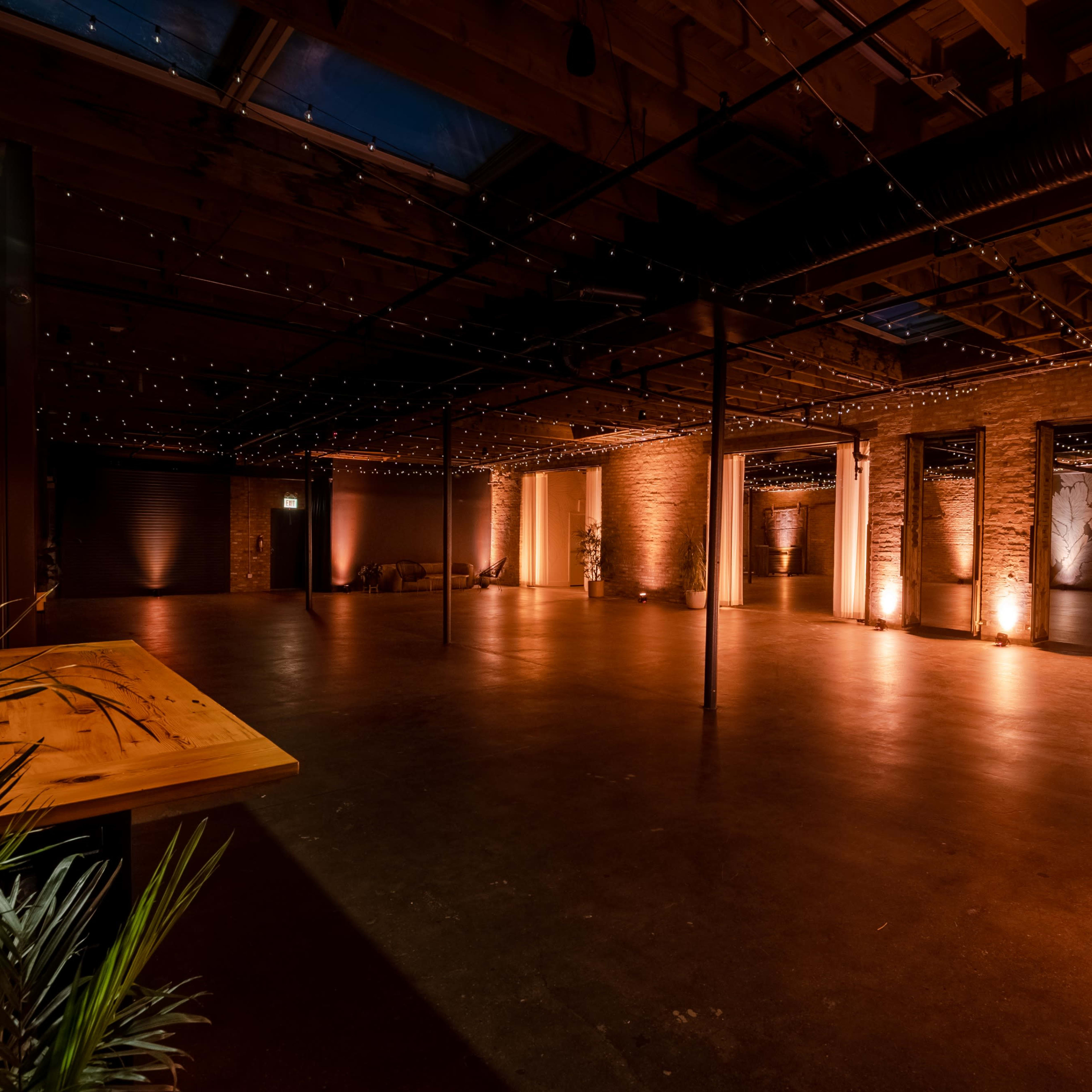 An empty indoor venue with exposed wooden beams, stone walls, and warm lighting.