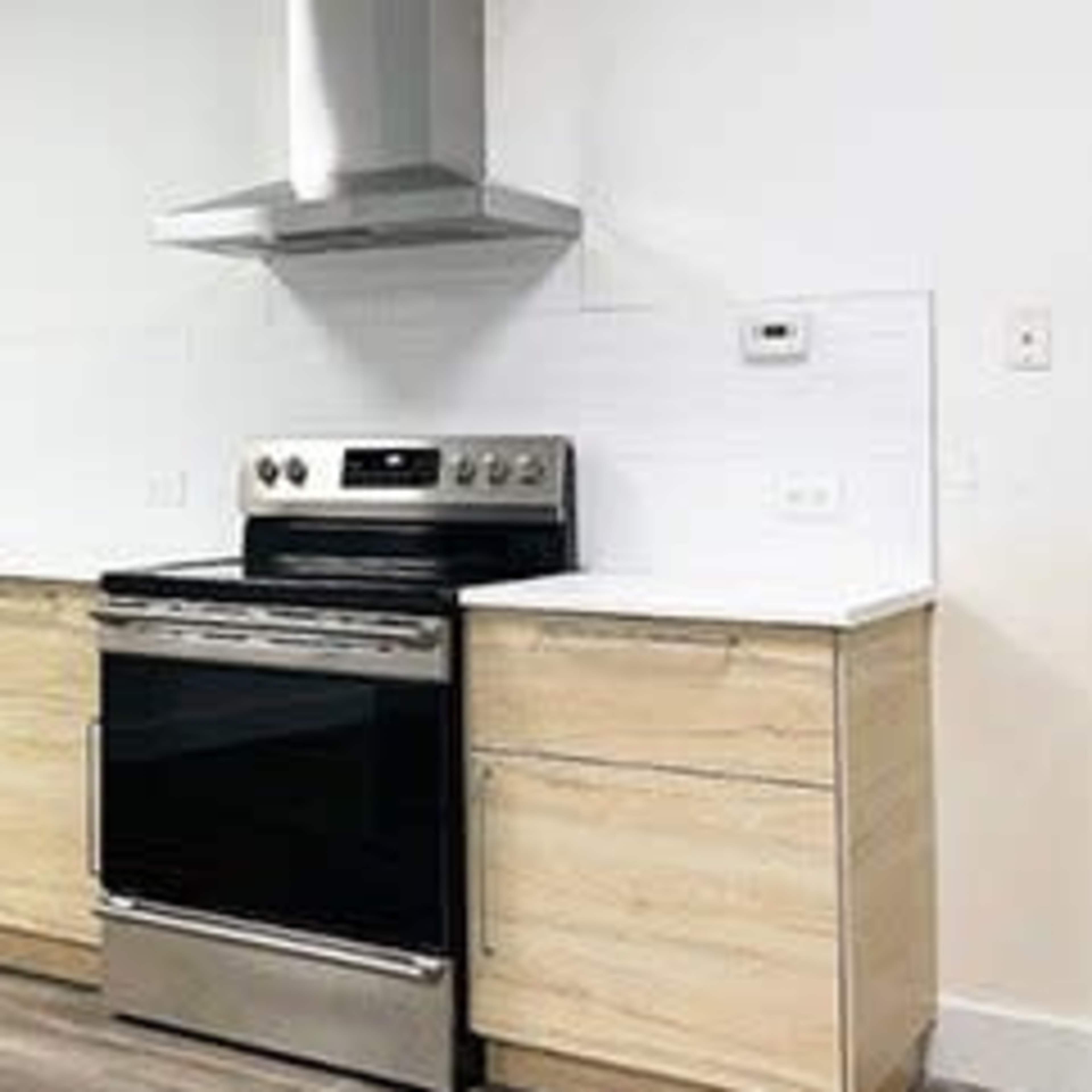 A modern kitchen featuring light wood cabinets, stainless steel appliances, and a white backsplash.