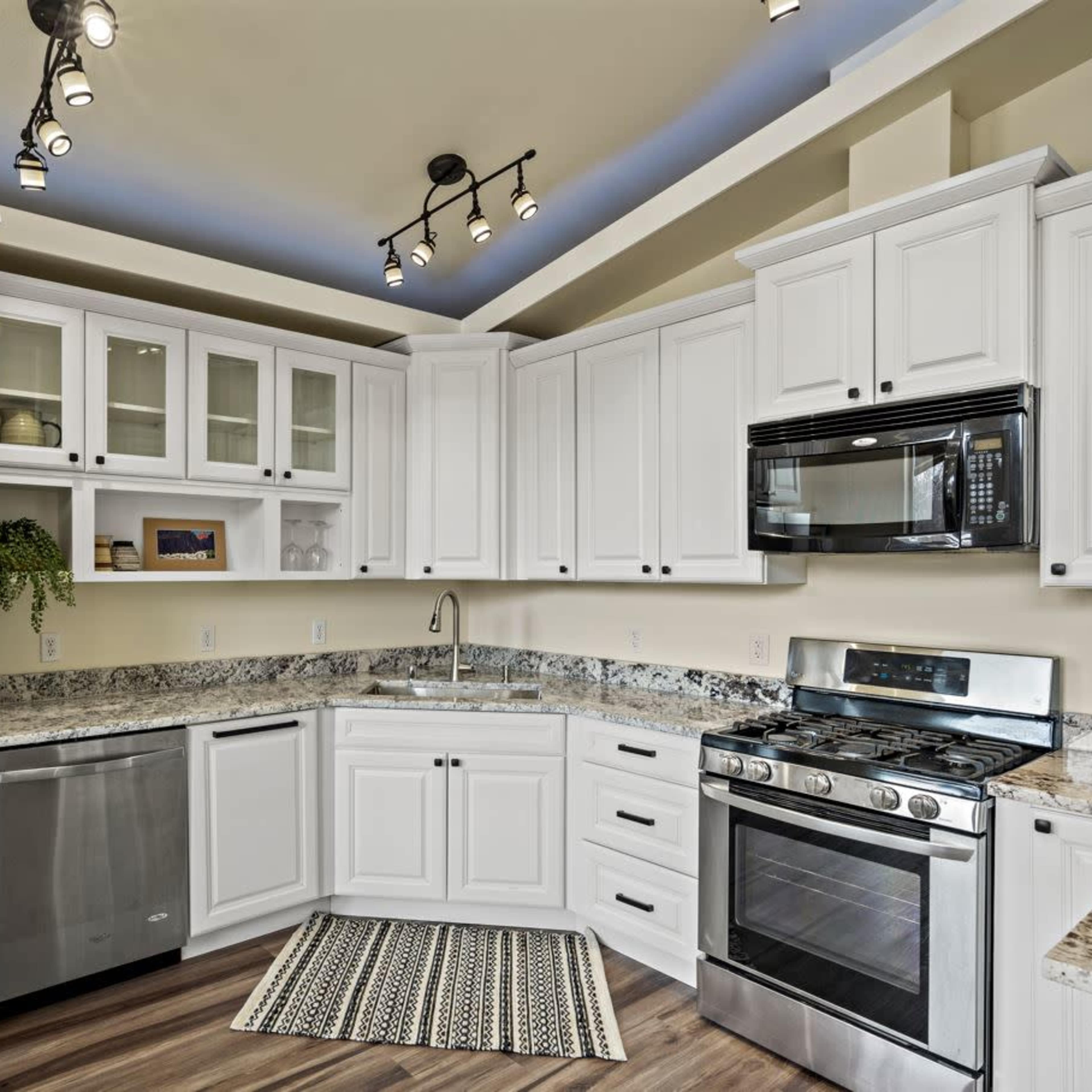 A modern kitchen featuring white cabinetry, stainless steel appliances, and a granite countertop.