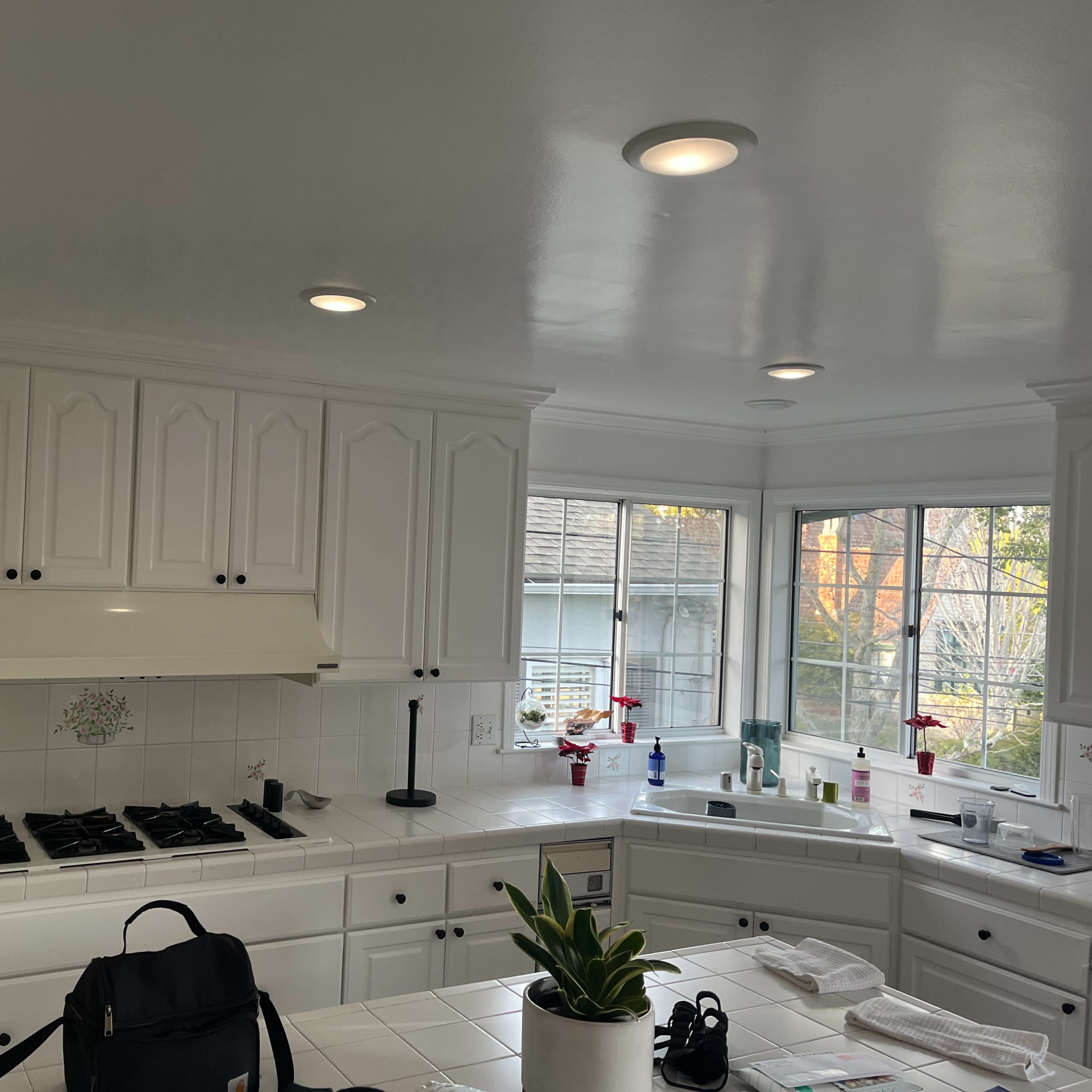 The kitchen features white cabinetry, a gas stove, and large windows providing natural light.