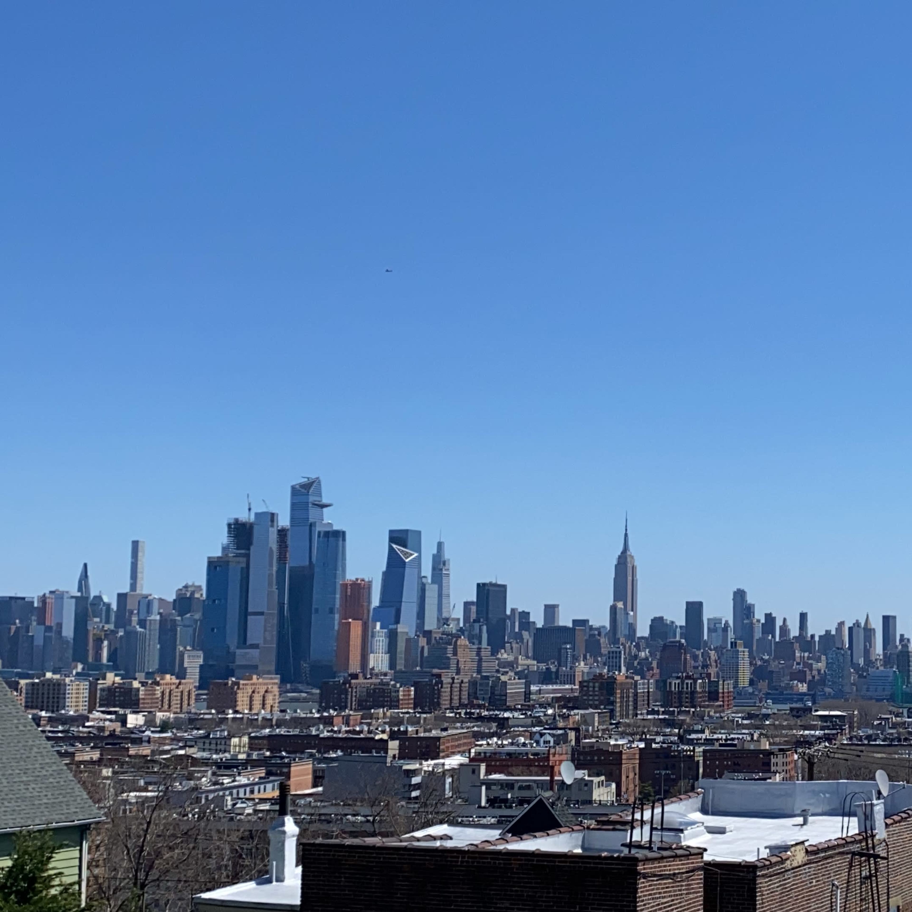 A clear view of a city skyline featuring tall buildings, including the Empire State Building, under a blue sky.