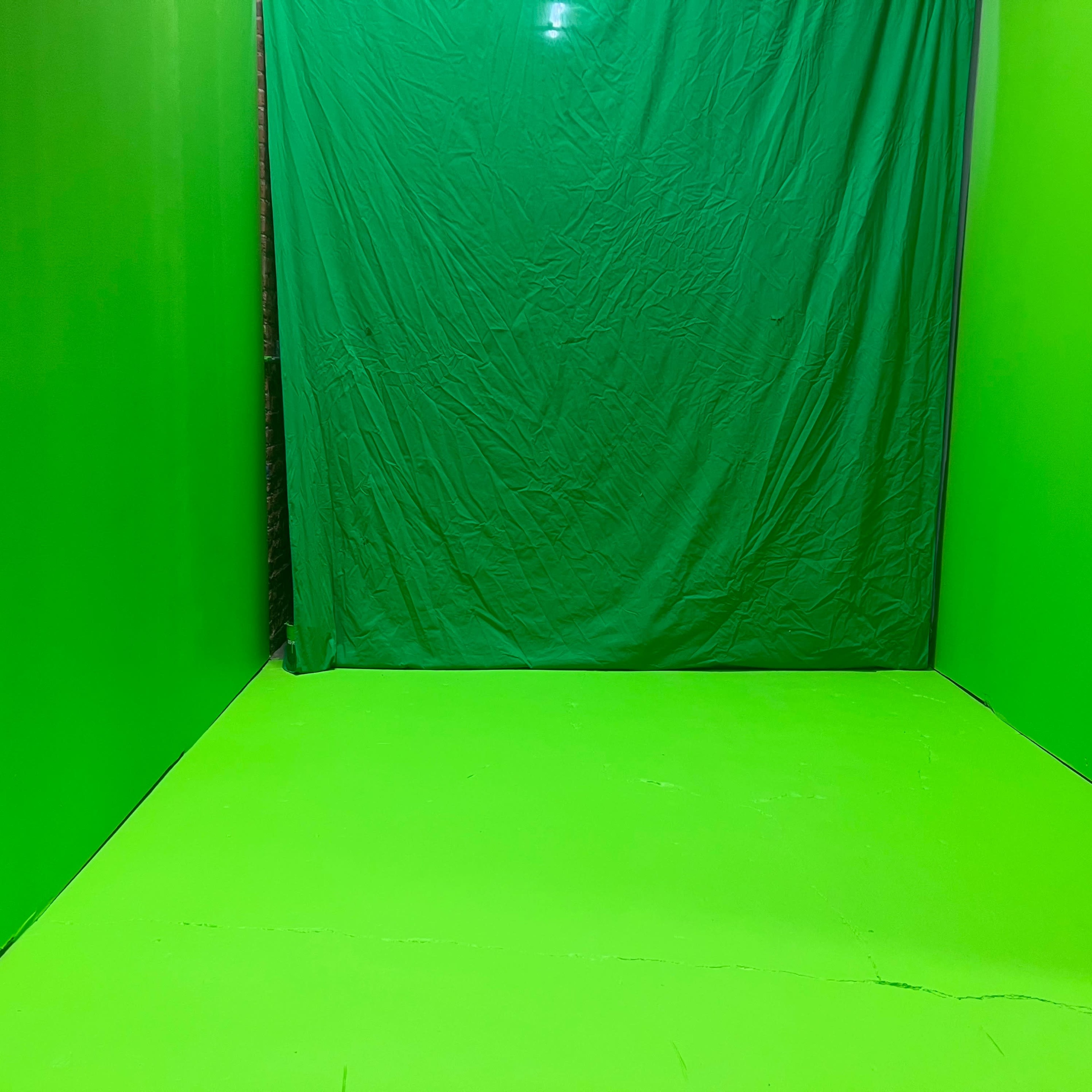 An empty room with green walls and a green floor, all covered in a fabric backdrop.