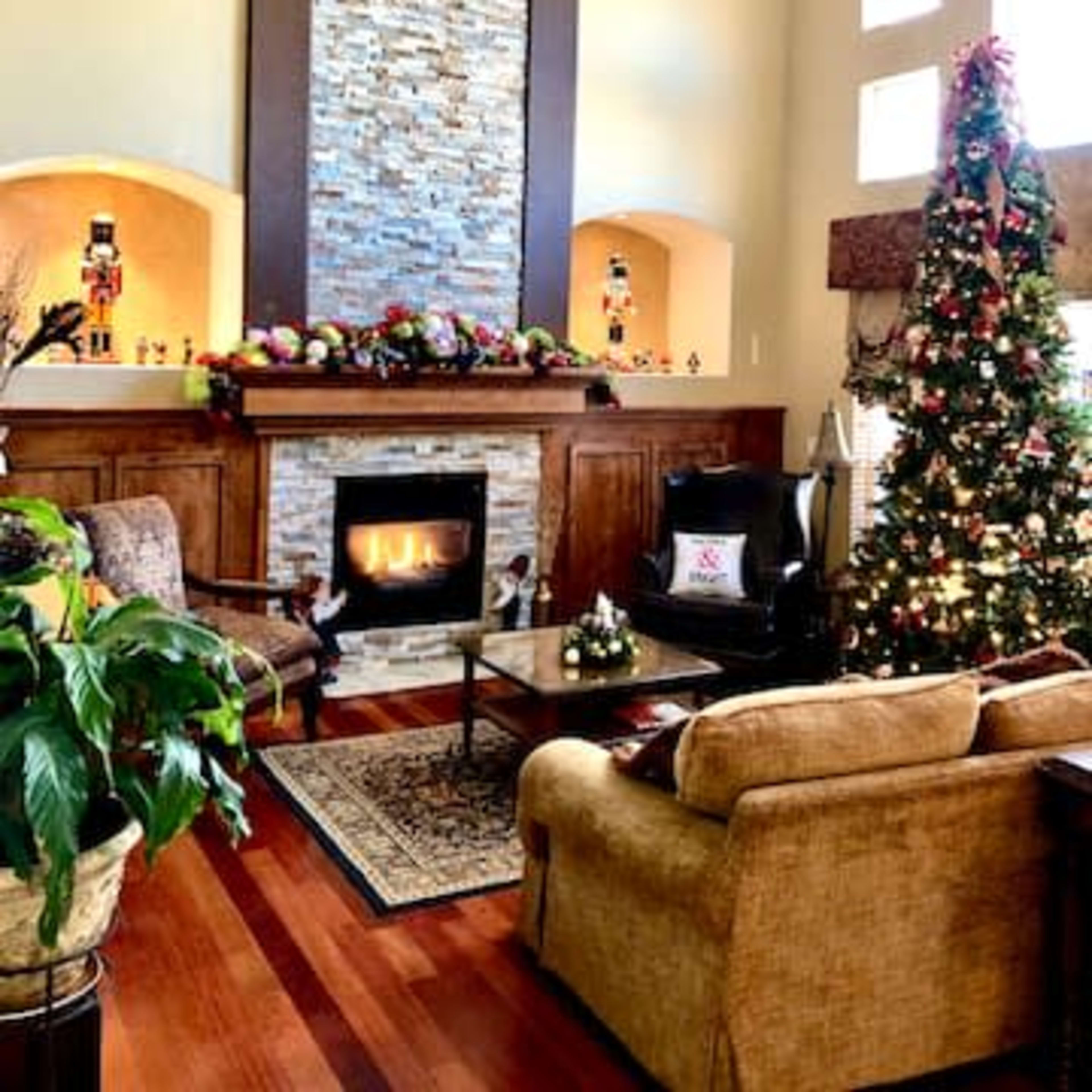 The living room features a stone fireplace with a mantel decorated for the holidays, a Christmas tree, and seating arranged around a coffee table.