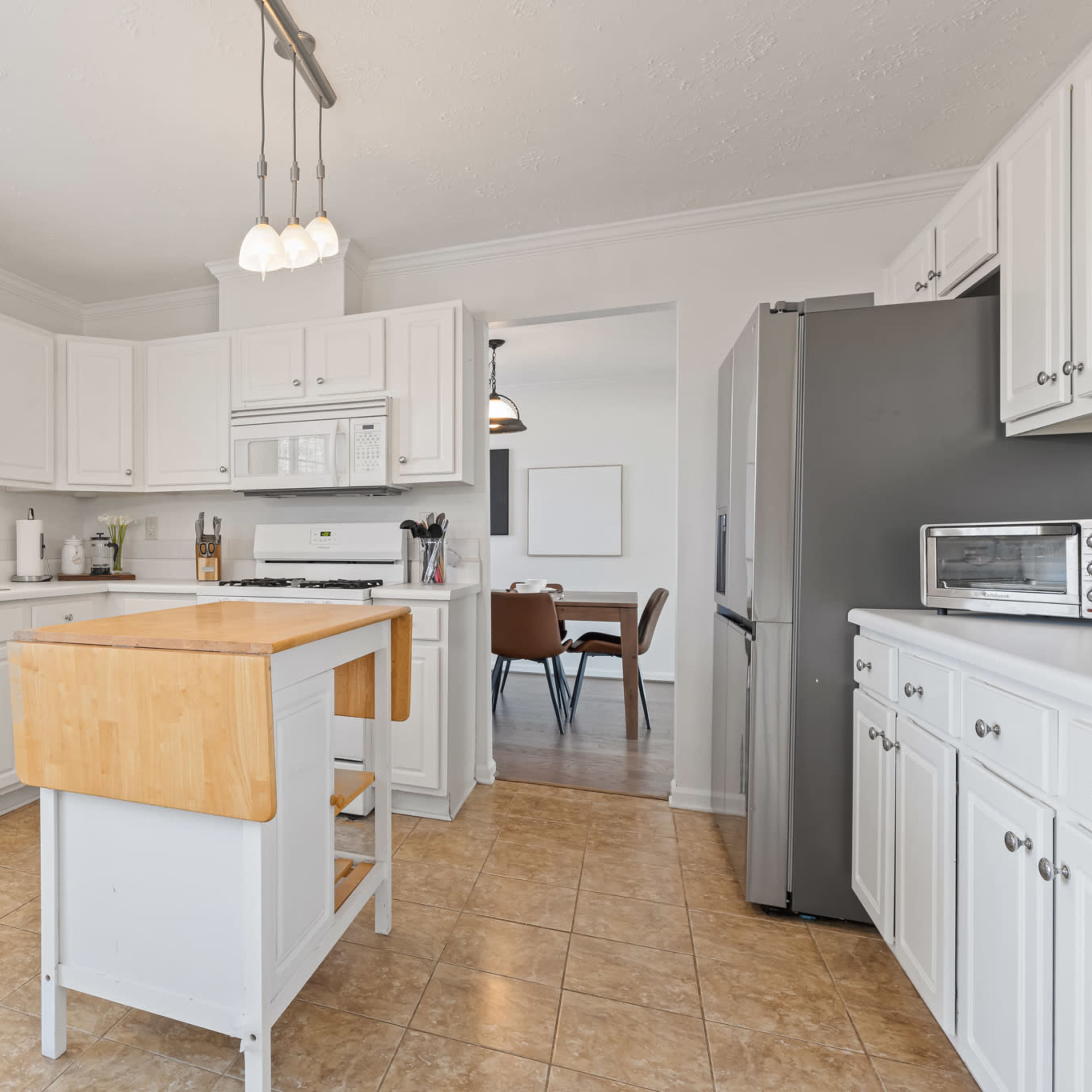 A bright kitchen with white cabinets, a central island, and stainless steel appliances.