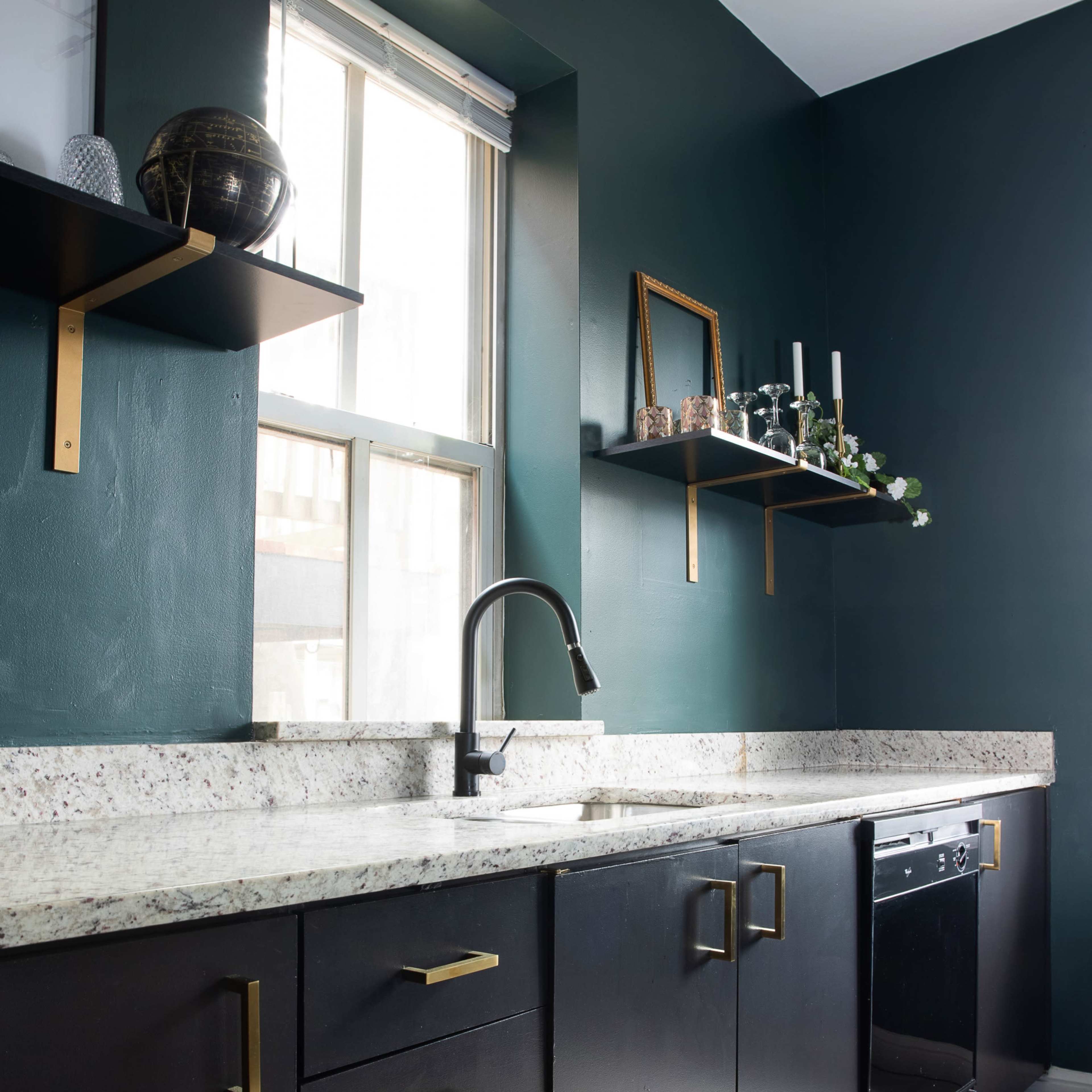 The kitchen features dark cabinetry, a speckled countertop, and wall-mounted shelves above a sink and dishwasher.
