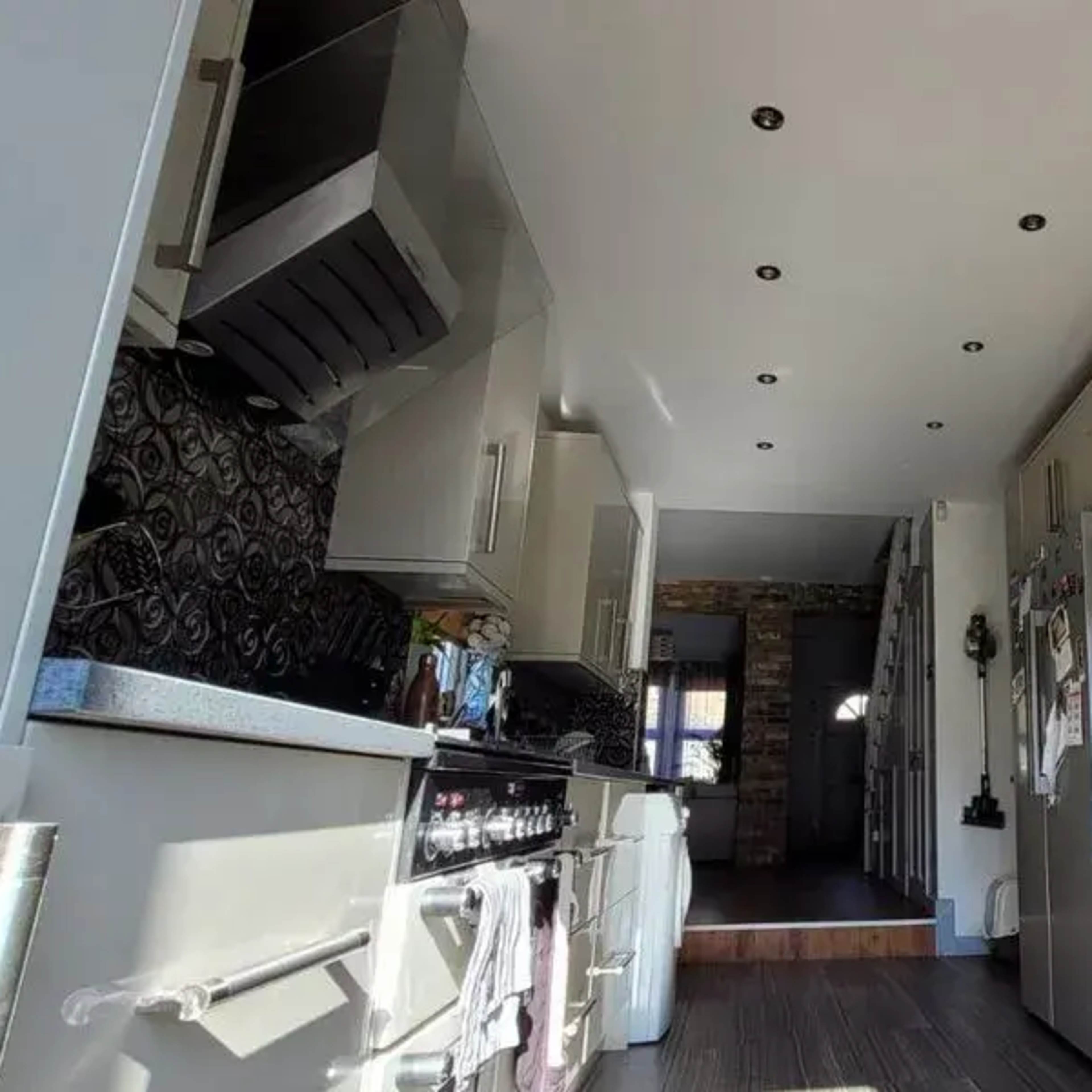 A modern kitchen with light-colored cabinets, stainless steel appliances, and a patterned backsplash.