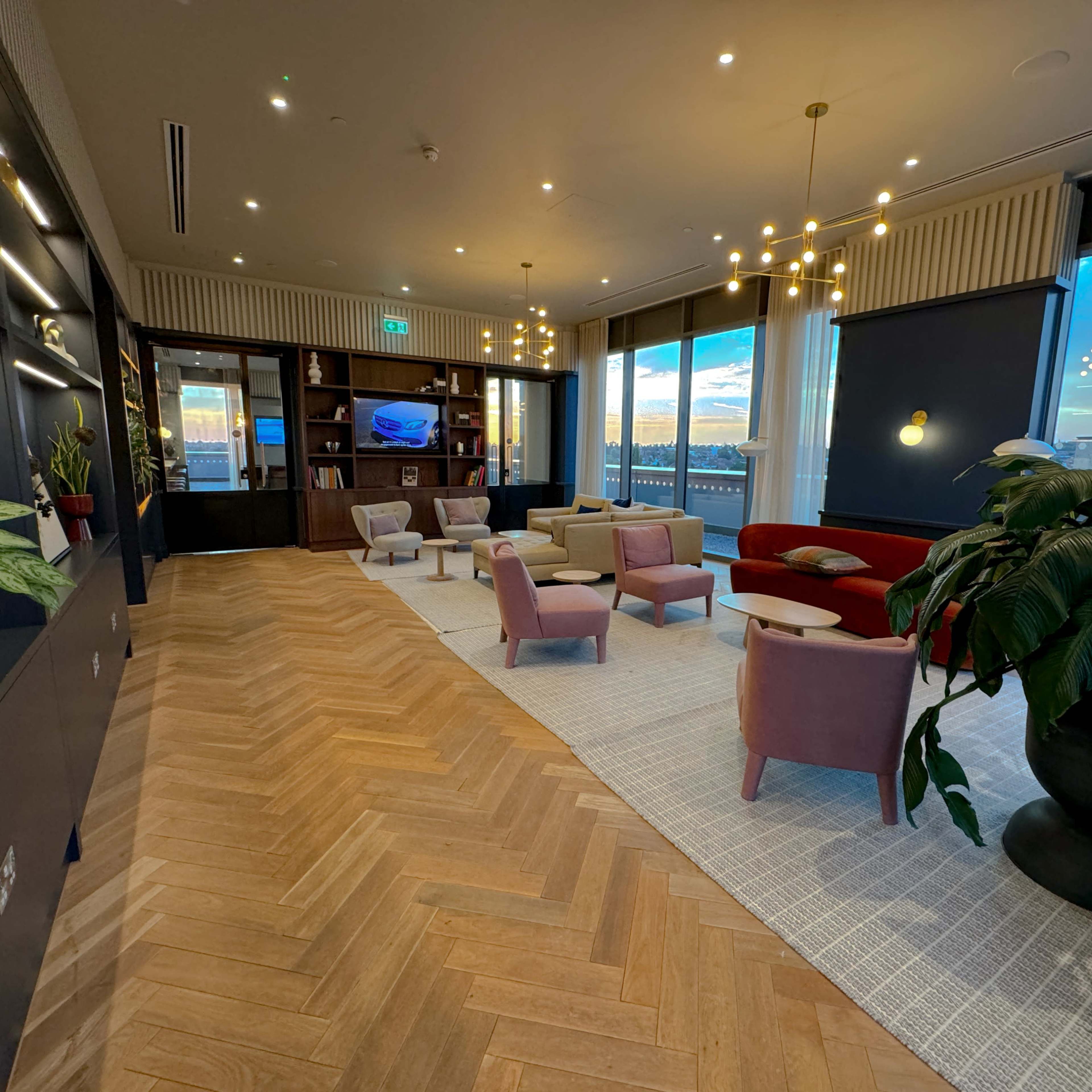 A modern lounge area with a mix of seating, plants, and large windows overlooking a scenic view.
