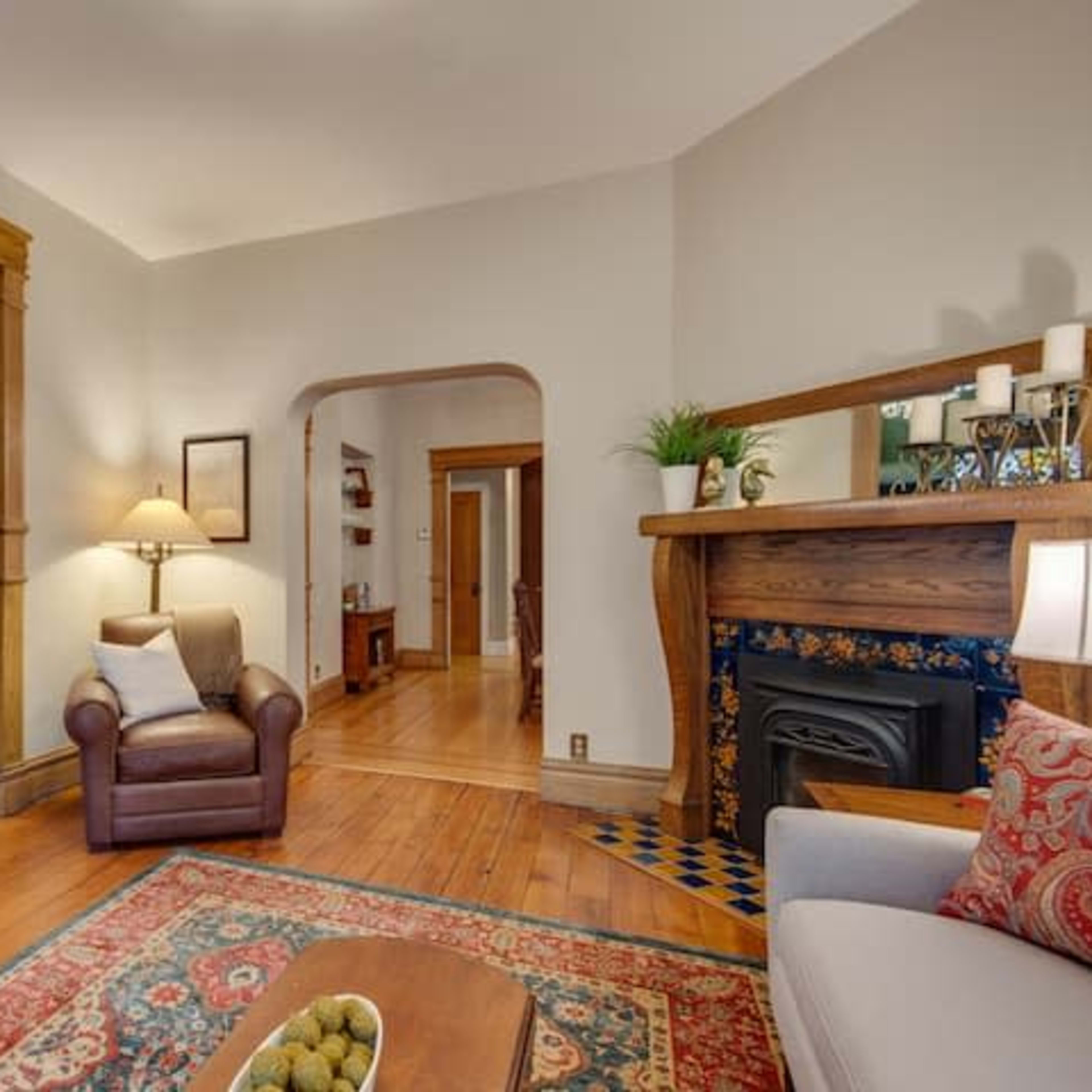 A cozy living room with wooden accents, a fireplace, and a view of a staircase leading to an upper level.
