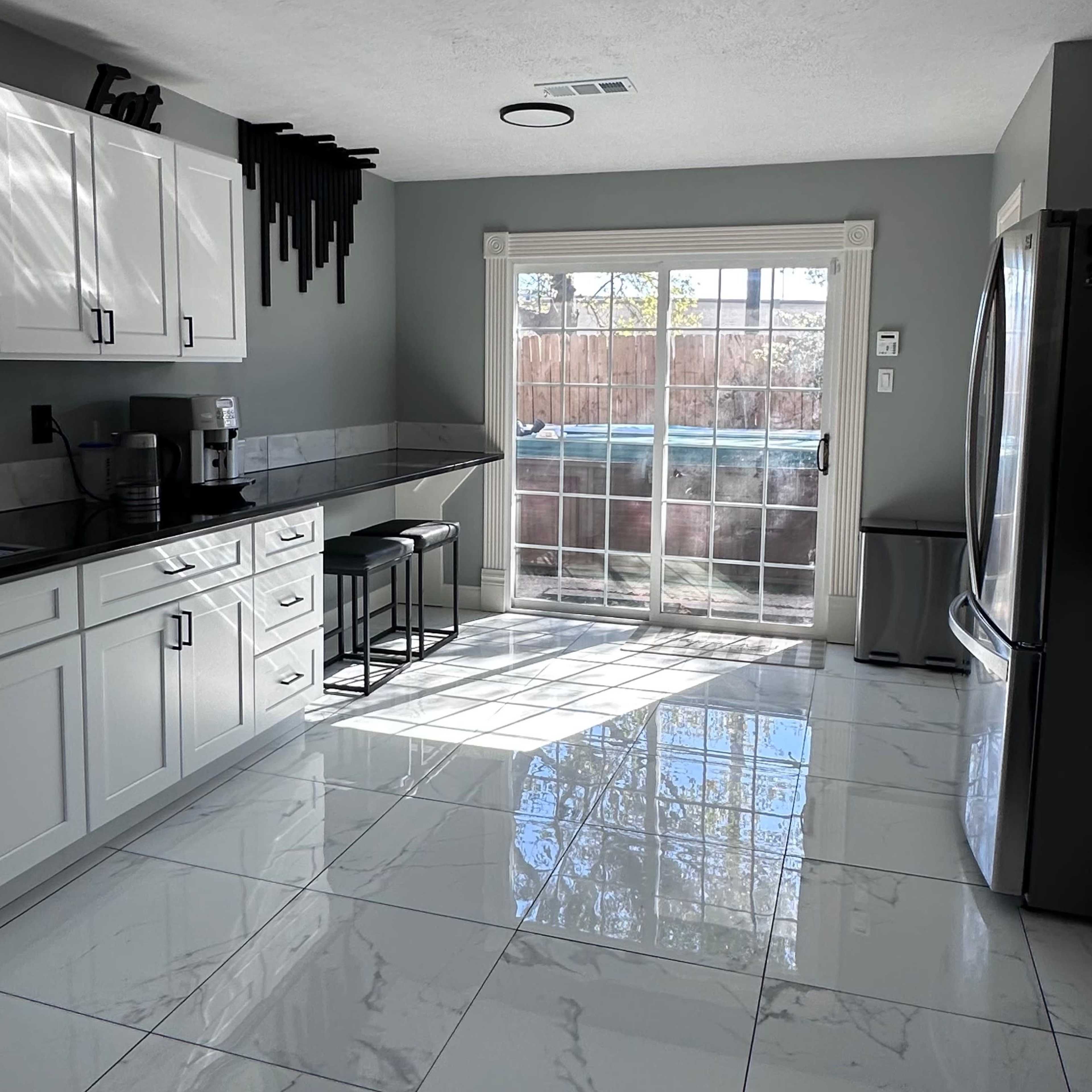 The kitchen features white cabinets, a gray countertop, and a large sliding glass door leading to an outdoor area.